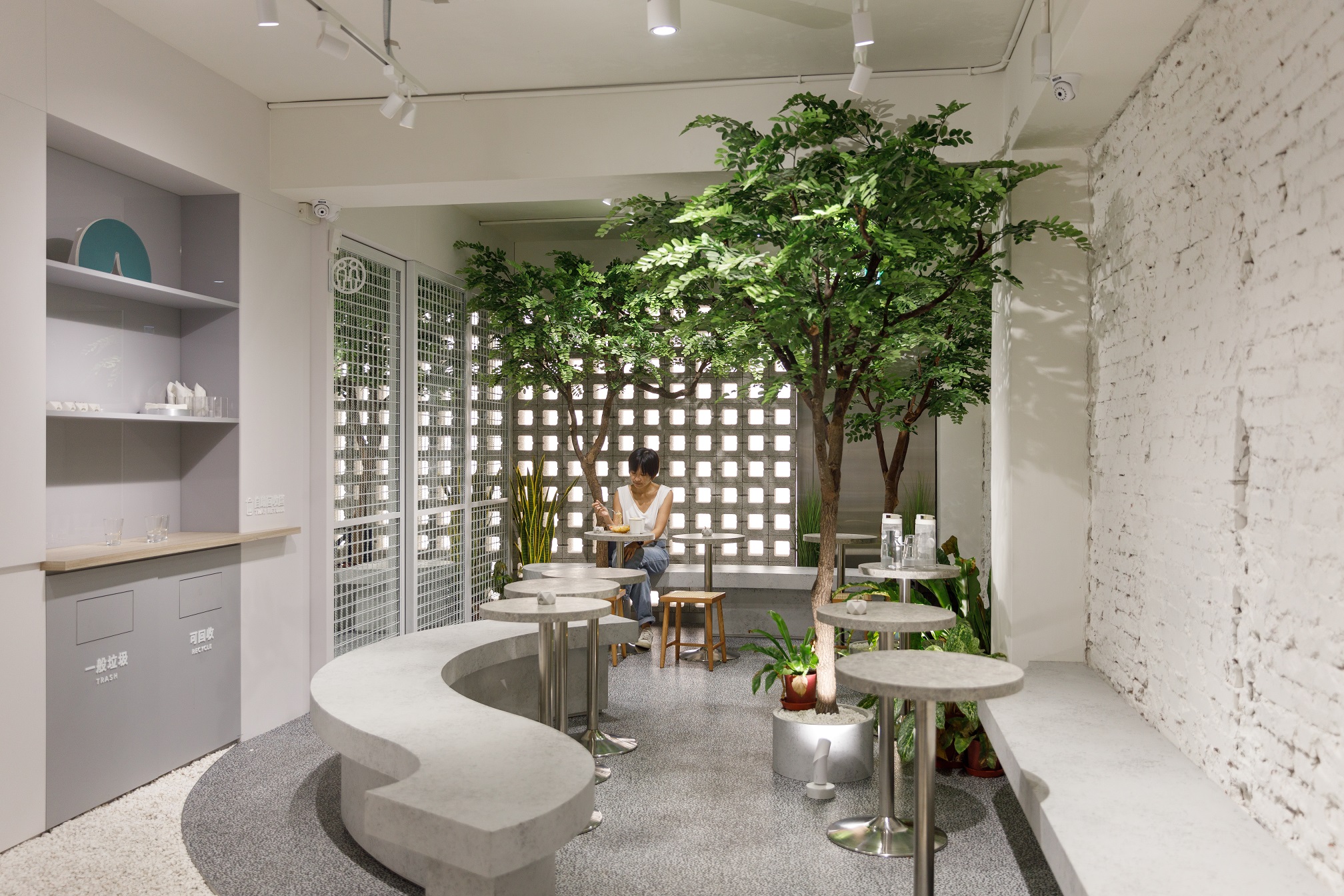 杉SHAN台北松山店以白牆、灰石與植栽創造出簡潔開闊的空間感。