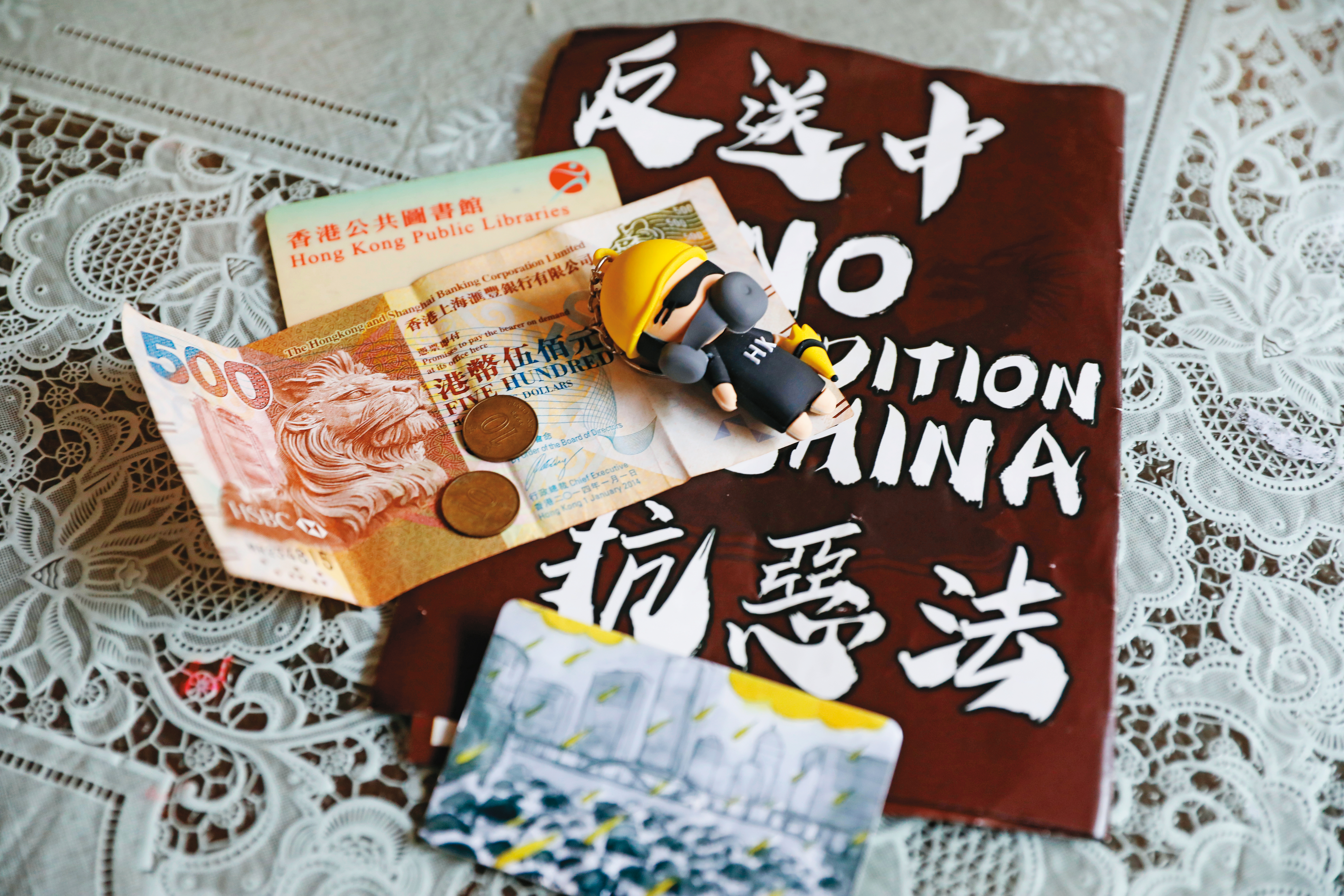 阿俊來台時帶在身上的港幣和圖書證，以及手足寄到台灣給他的戴防毒面具公仔。