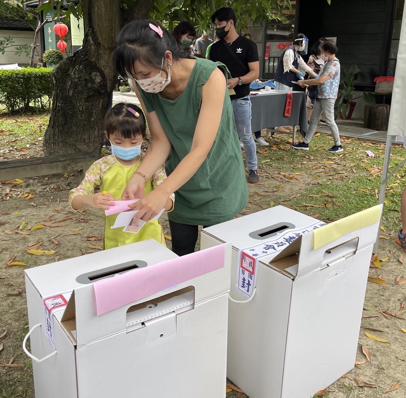 越南新住民玉燕教導孩子選票要對折後再投入票匭，避免亮票或選票卡在票匭。（嘉義市服務站提供）