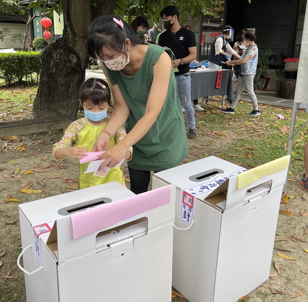越南新住民玉燕教導孩子選票要對折後再投入票匭,避免亮票或選票卡在票匭。(嘉義市服務站提供)