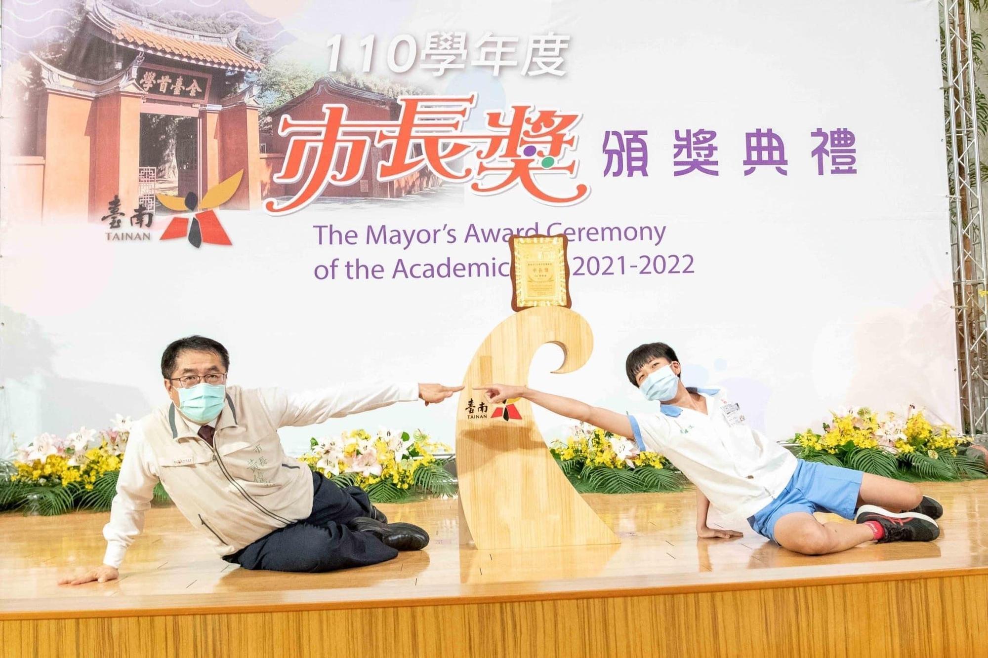 黃偉哲和學子合照,配合擺出名畫「創世紀」的姿勢,展現親和力。(台南市政府提供)