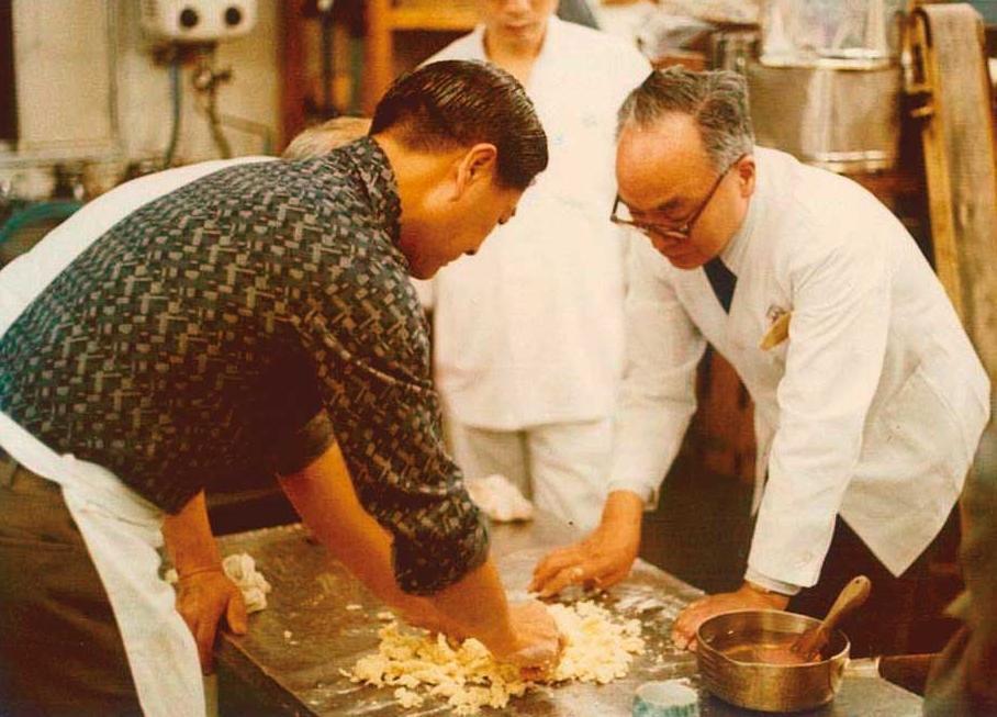 1980年，日本天皇御廚板垣正二（右）到不二家擔任顧問，教導製作蜜紅豆等日式技藝。（不二緻果提供）