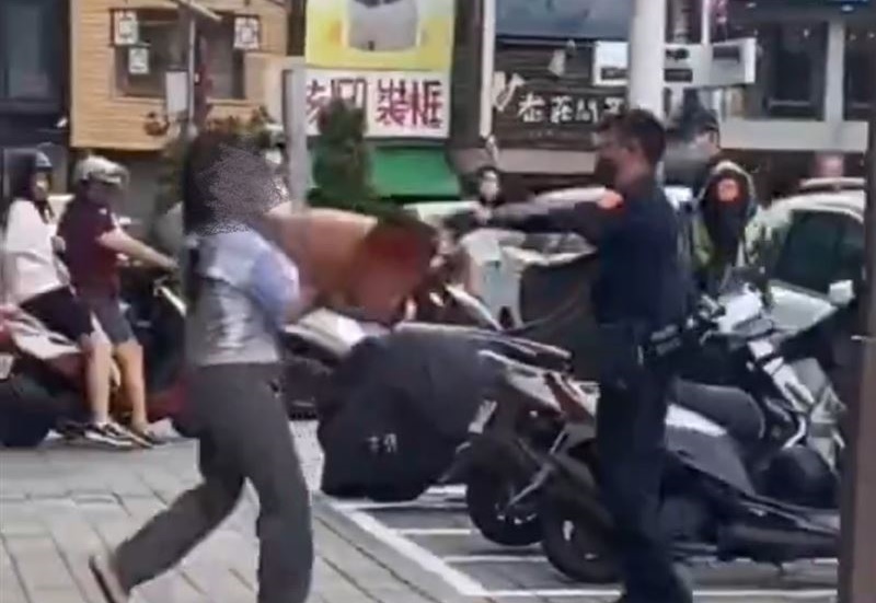 吳女持路邊的交通錐試圖砸員警，最後被壓制在地。（翻攝社會事新聞影音）