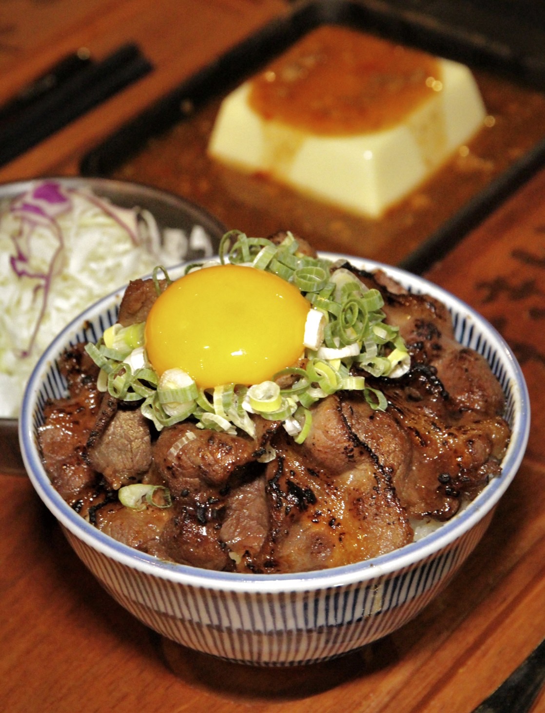 經典的「日出燒肉丼」完美展現蛋液與燒肉片的契合度，「鐵板麻婆豆腐」則是選用令醬汁更入味的雞蛋豆腐，滑嫩化口。（日出燒肉鐵板定食290元起／份，鐵板麻婆豆腐定食250元起／份）