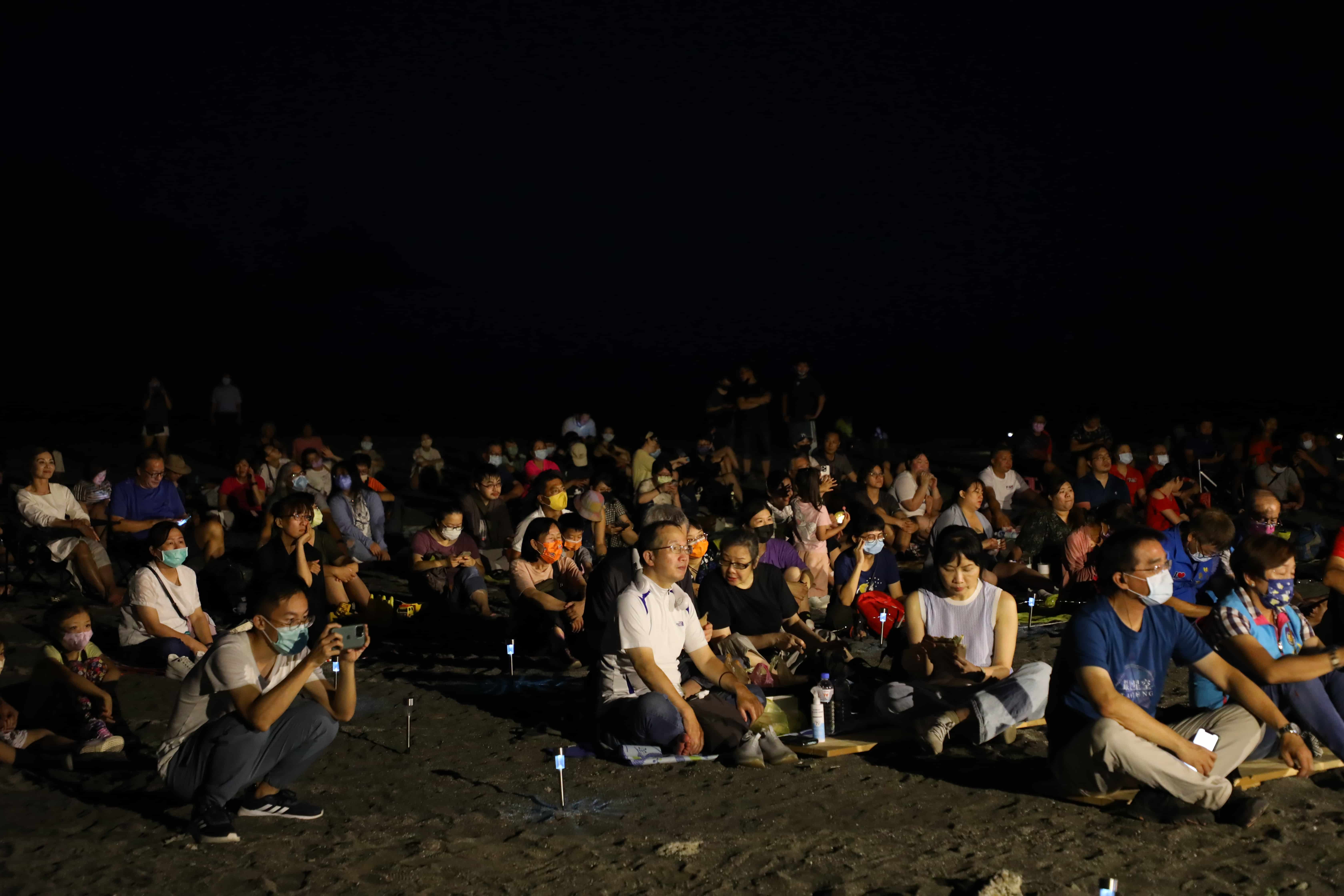 現場民眾排排坐在沙灘上，閒逸享受星空與表演加乘的美好時光。