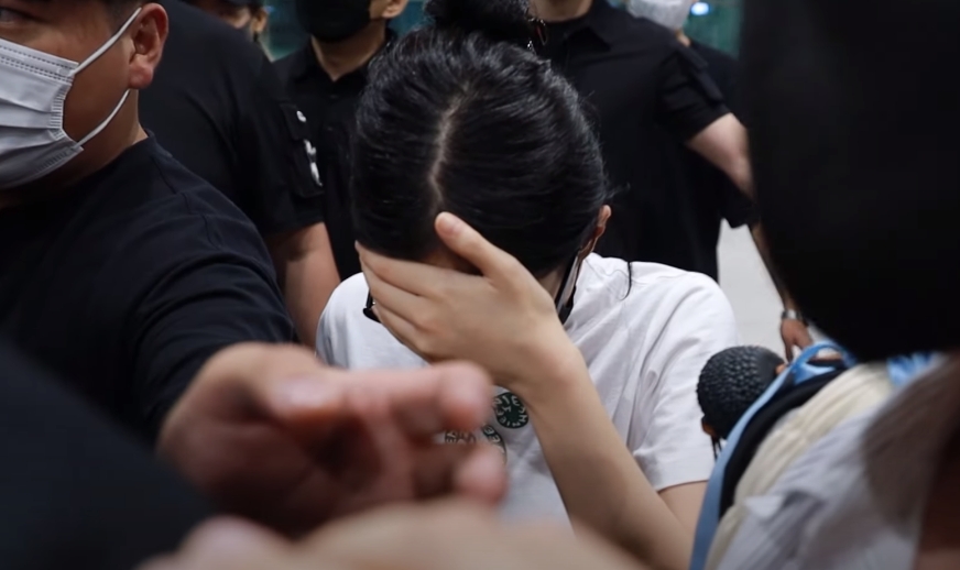 Jennie在機場被媒體包圍,面容相當憔悴,頻頻以手扶住額頭,上保母車前疑似有呼吸困難的狀況。(翻攝自NEWSEN YouTube頻道)