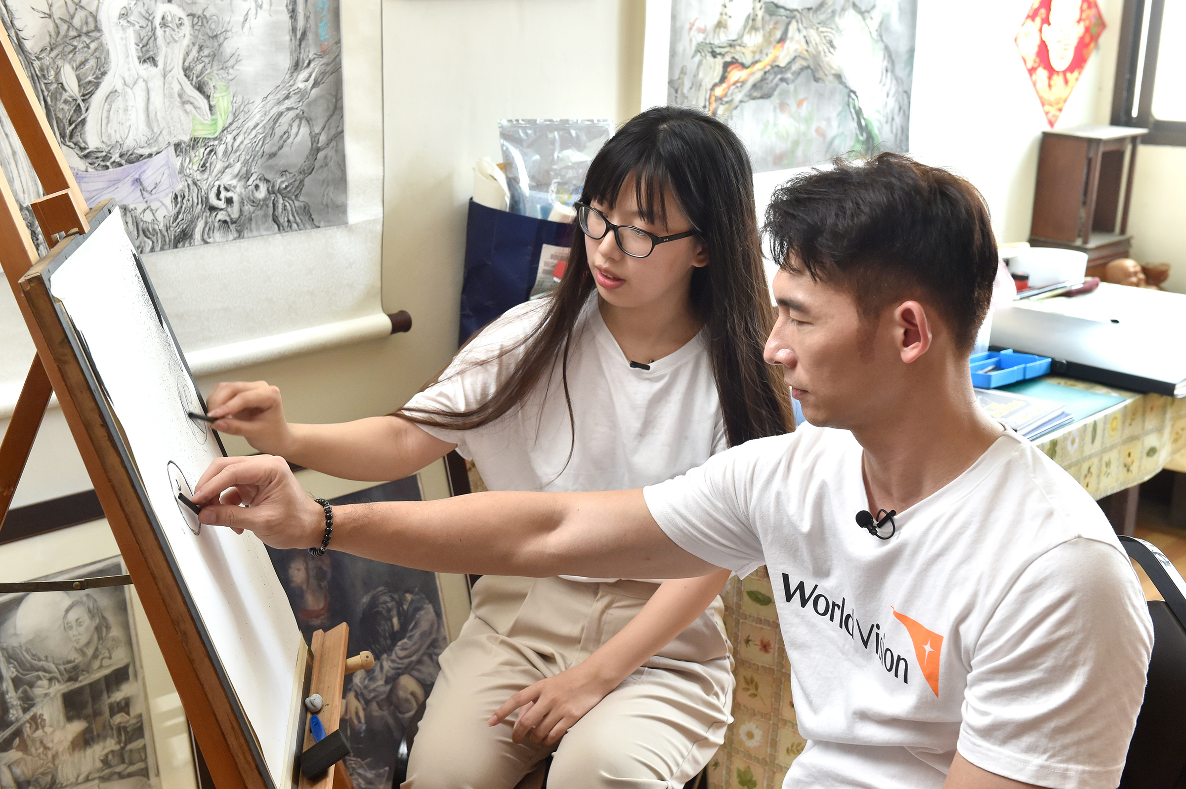 温昇豪聆聽小妤的創作故事,向小妤學用炭筆畫蘋果。(台灣世界展望會提供)