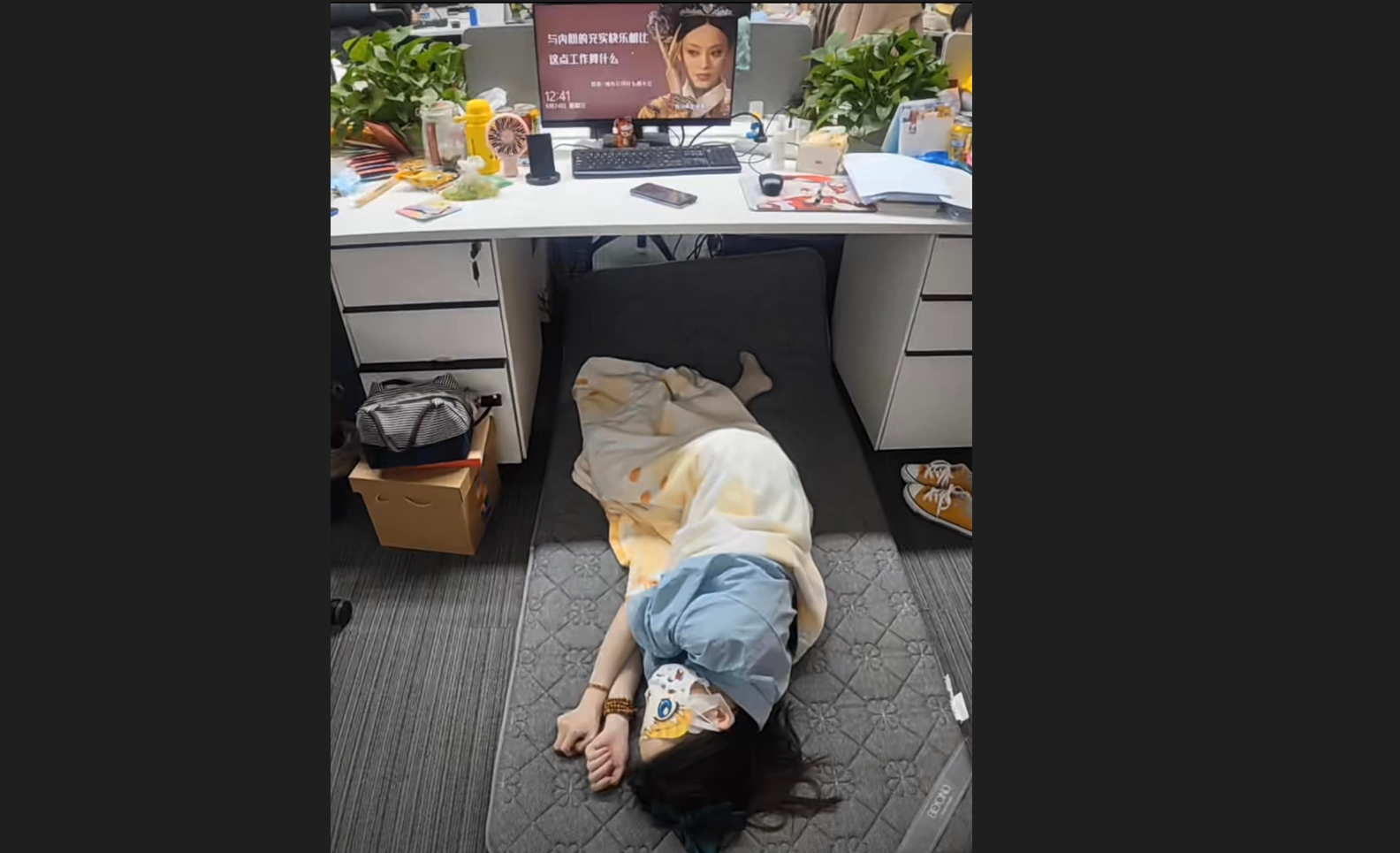 一名女性上班族把辦公室當自家,直接在辦公桌下鋪睡墊、蓋被子、戴眼罩午睡。(翻攝《爆廢公社公開版》)