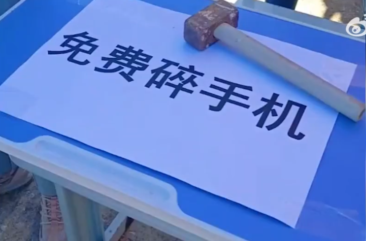 中國河北某中學校管制學生帶手機進入校園，門口擺桌並張貼「免費碎手機」標語。（翻攝《巨浪視頻》）