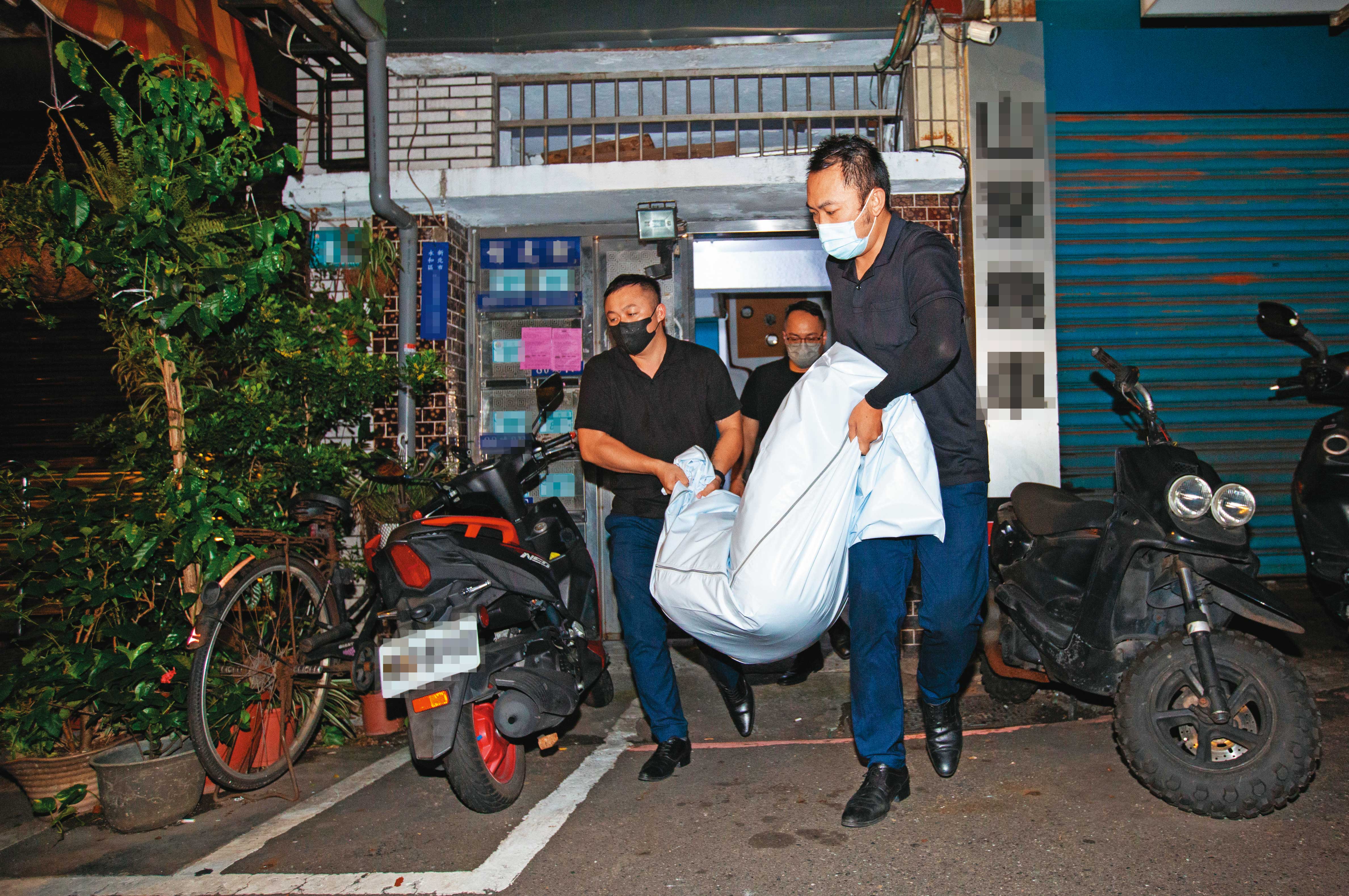 葬儀社人員將死者殘存大體從公寓搬下樓，準備運往殯儀館等候相驗。