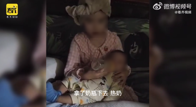 6歲小姊姊抱著2個月大的弟弟，手拿奶瓶餵奶，姿勢專業。（翻攝微博@梨視頻）