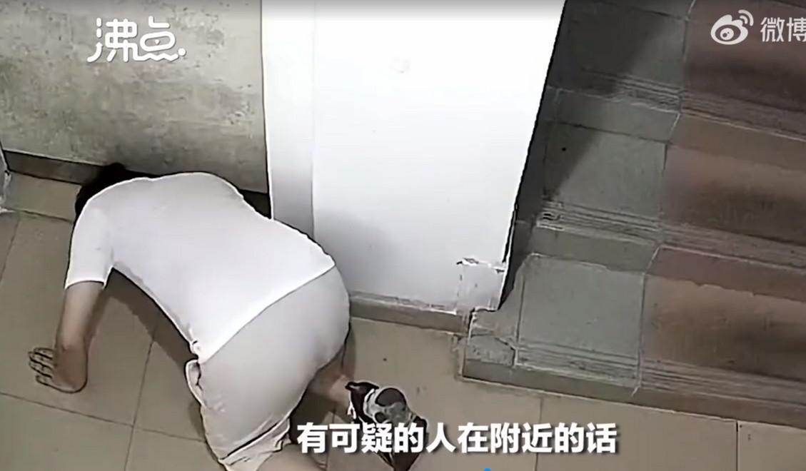 中國廣東省男子深夜趴在地上從門縫偷窺房內動靜。（翻攝自《沸點視頻》）