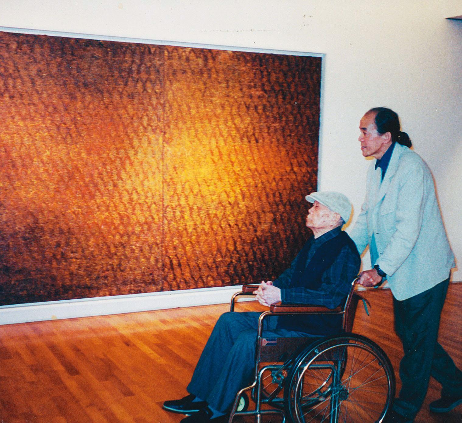 1998年江賢二在誠品畫廊舉辦個展,他推著坐輪椅的父親參觀,此幅畫亦為百年廟系列,他將光明燈入畫。(江賢二提供)