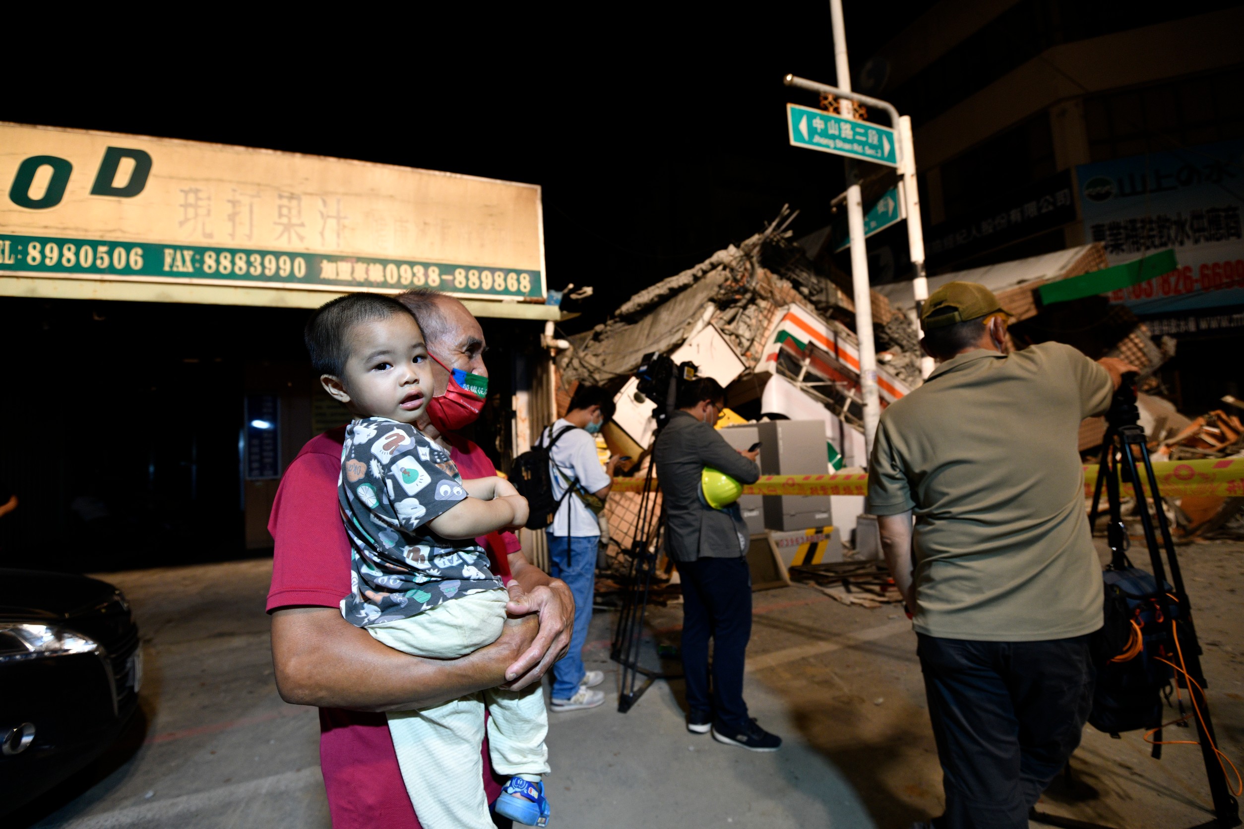 倒塌的超商樓房一旁住戶也受到餘震和停電影響，大人小孩夜深了仍不敢回家。（李智為攝）