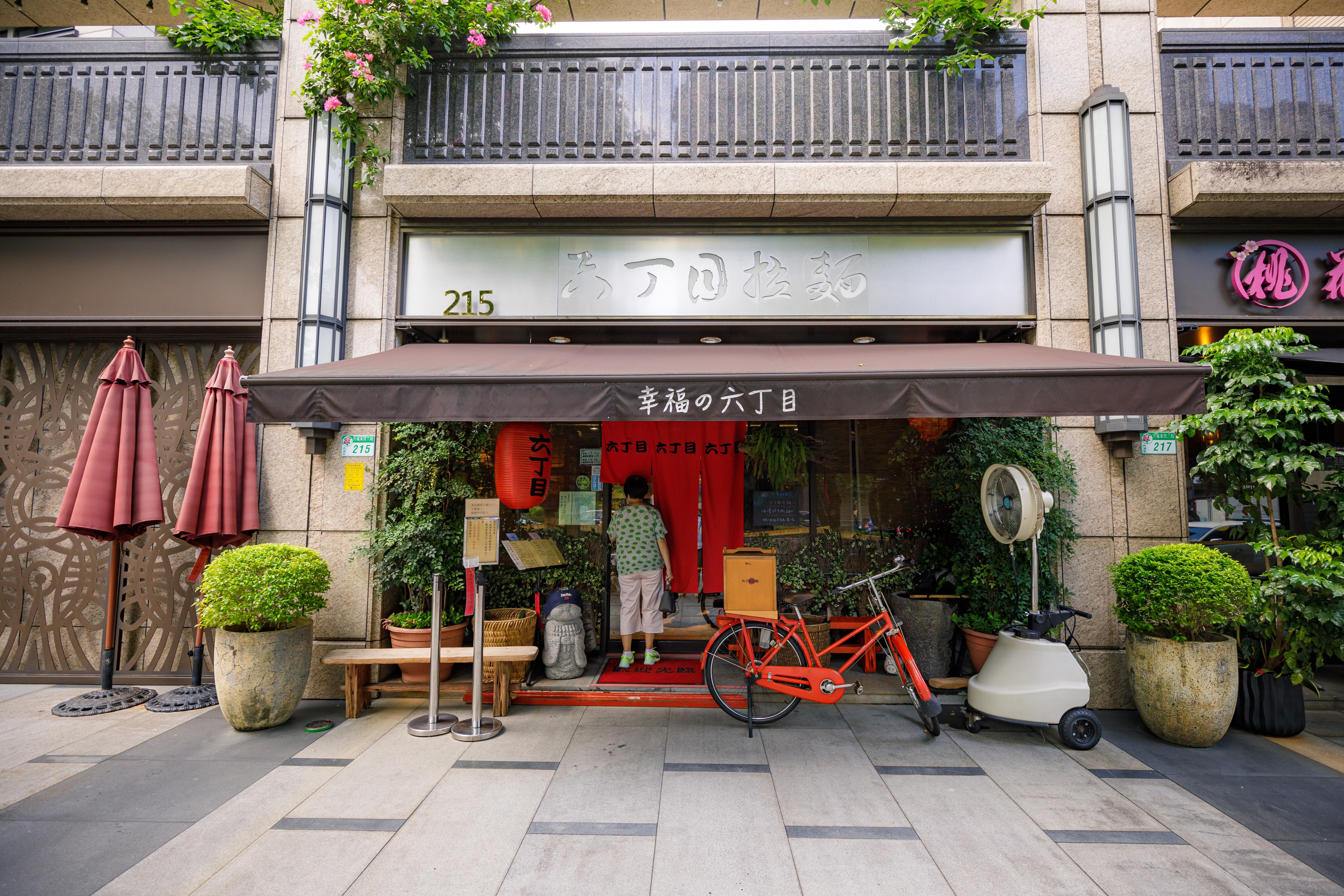 「六丁目拉麵」門口備有大遮陽傘、風扇，為排隊客人降溫擋雨。