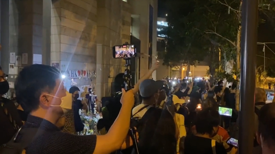 香港英國總領館外有男子吹口琴悼念英國女王，引起眾人共鳴，卻因遭警方逮捕。（翻攝自推特）