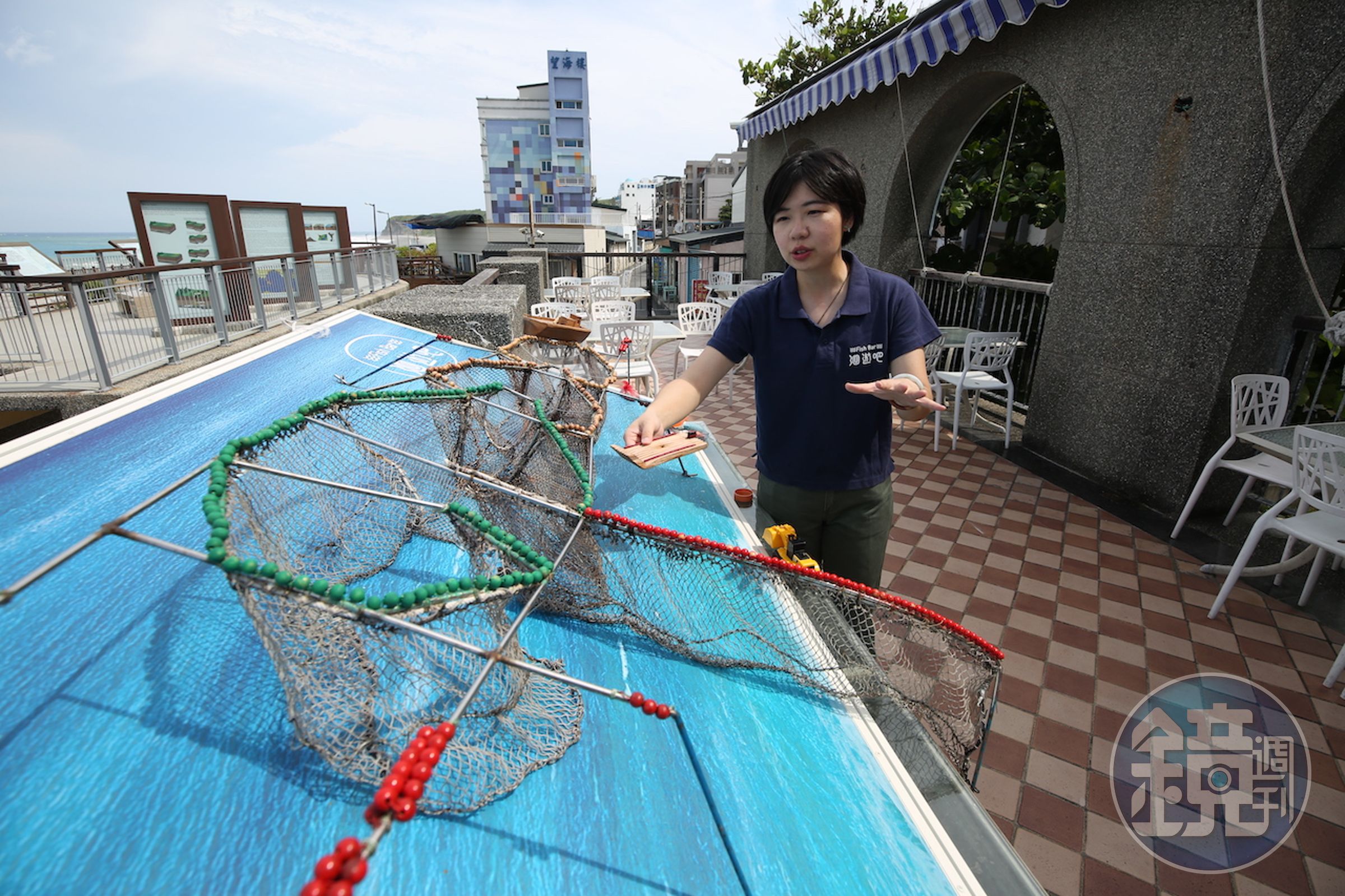 創辦人暨執行長黃紋綺在「洄遊吧」戶外架設一座「定置漁場」教具，正對大海講解友善漁法的重要性。