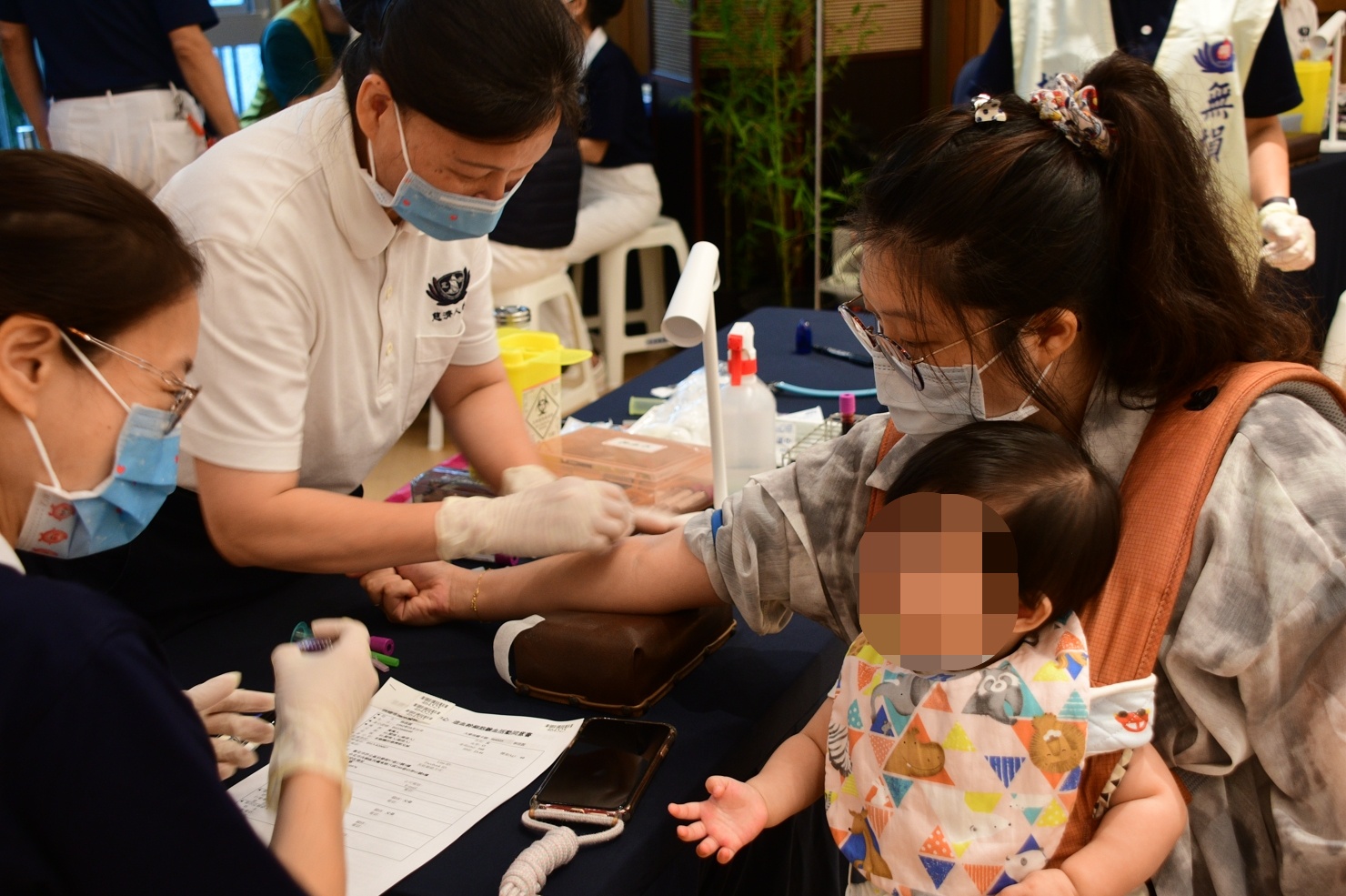 年輕的媽媽救人不落人後，帶著小嬰兒到場響應驗血建檔。（慈濟基金會提供）
