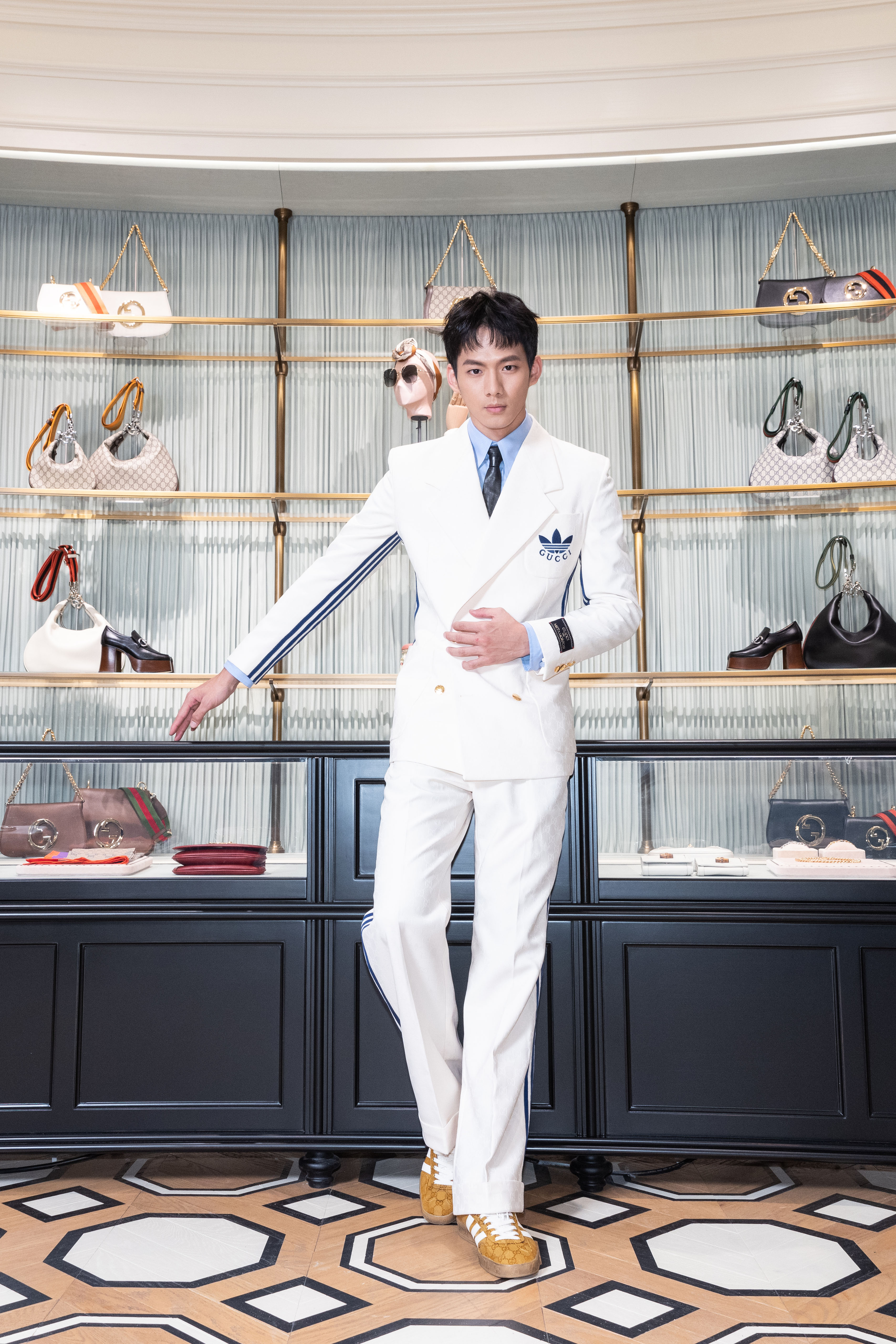 吳念軒身穿adidas x GUCCI白色雙排扣西裝外套NT$98,300、藍色襯衫NT$22,700、 adidas x GUCCI白色西裝褲NT$51,400、黑色皮革領帶NT$18,100、adidas x GUCCI棕色GG緹花運動鞋NT$28,400。（古馳提供）