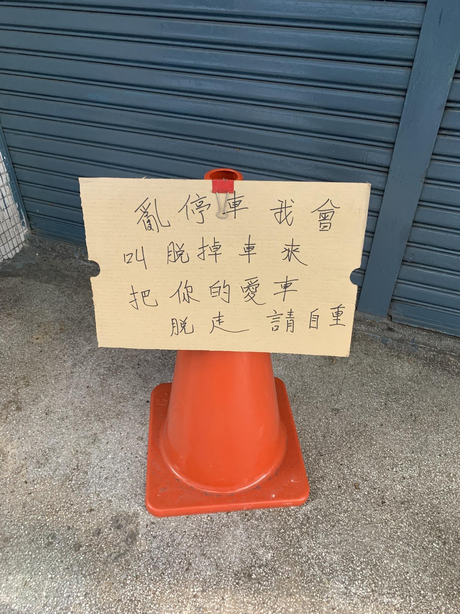有網友貼出一張三角錐的照片，上頭擺放手寫的「告示」防止別人亂停車，但告示上的「拖吊」竟寫錯成「脫掉」。（翻攝自路上觀察學院臉書粉專）