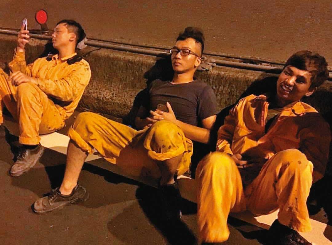 20多歲時的小姜(中)曾是塔吊工人,午夜到工地拆完塔吊台,與同事累坐路邊。(小姜提供)