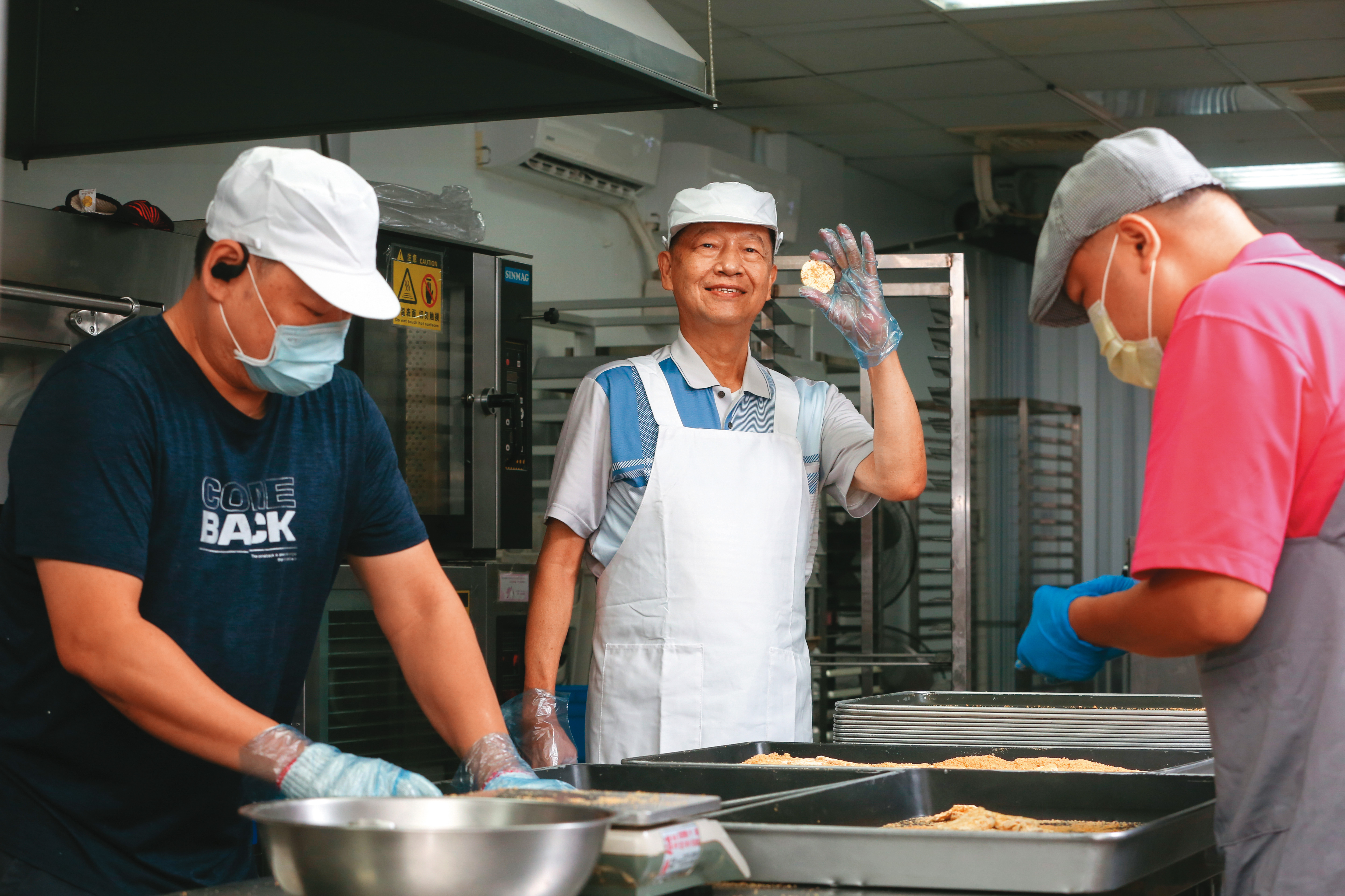 黃永吉（中）2005年意外研發圓片牛軋糖，表面沾了一層花生粉，軟香Q不黏牙口感大受歡迎，成為喜之坊最熱賣品項。