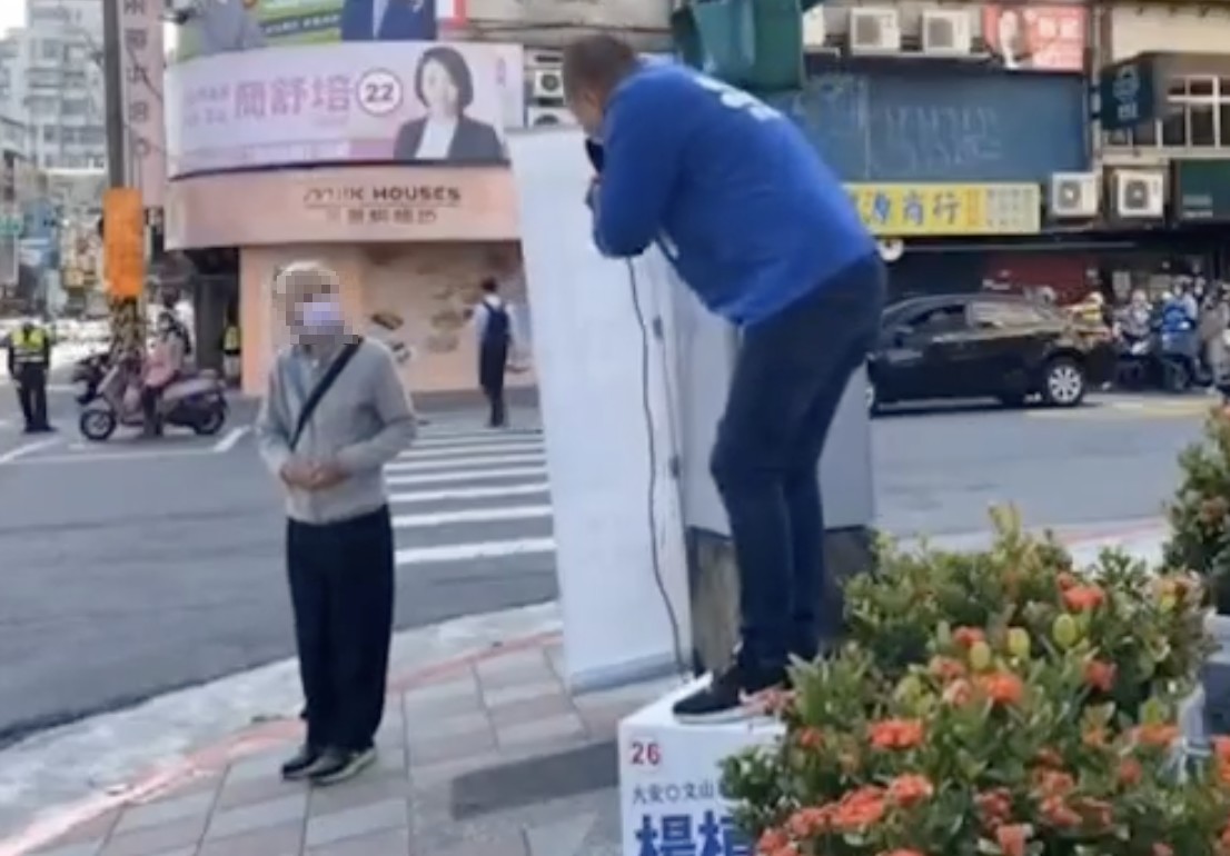 楊植斗今在路口拜票時，不慎從演講台上摔落。（截圖自羅智強臉書）