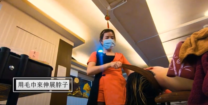 美容師透過毛巾拉扯施力，將後頸的筋活絡放鬆。