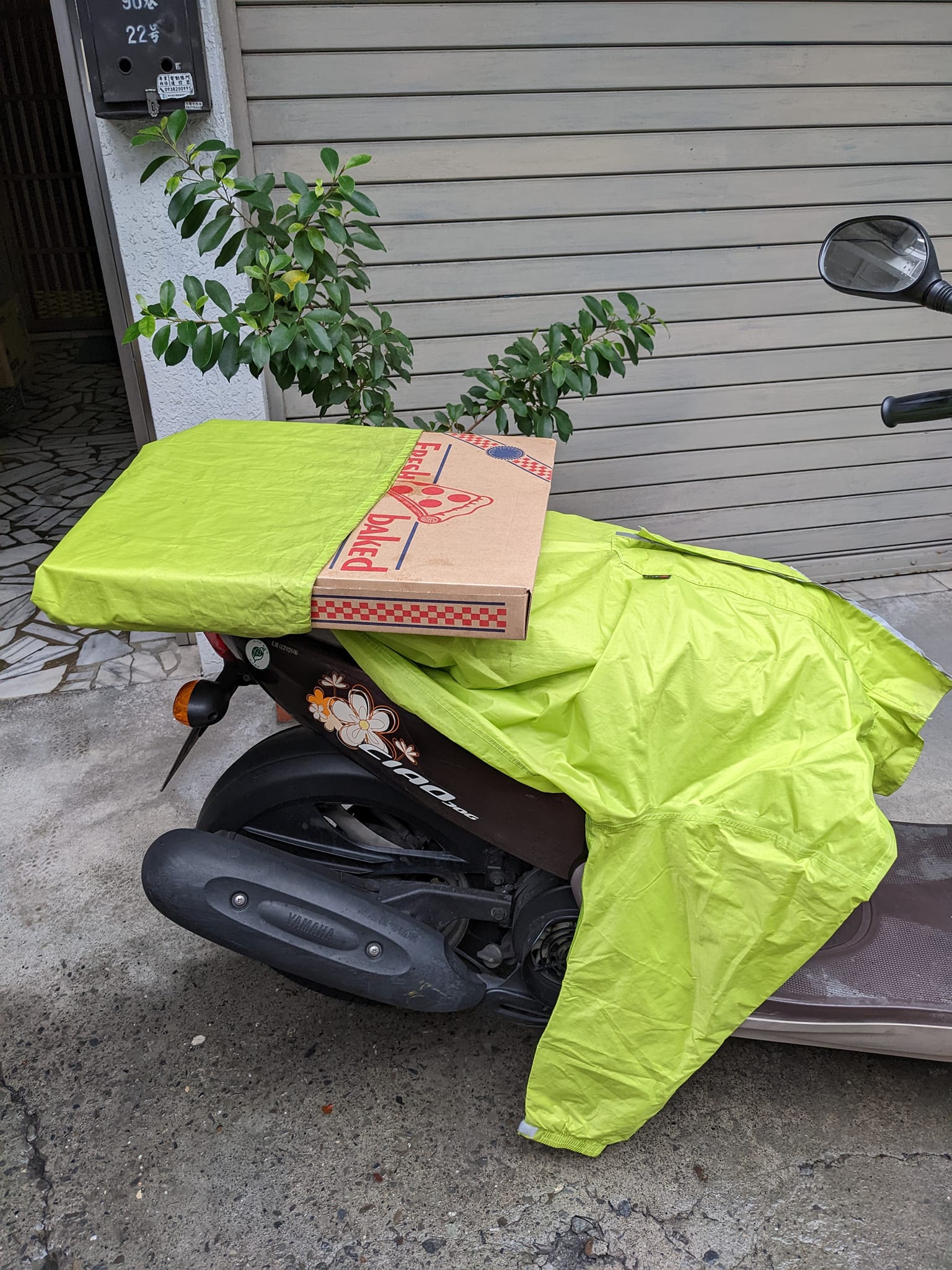 有網友分享如何用一件雨衣將整盒大披薩綁在機車後座。（翻攝自Costco好市多 商品經驗老實說）