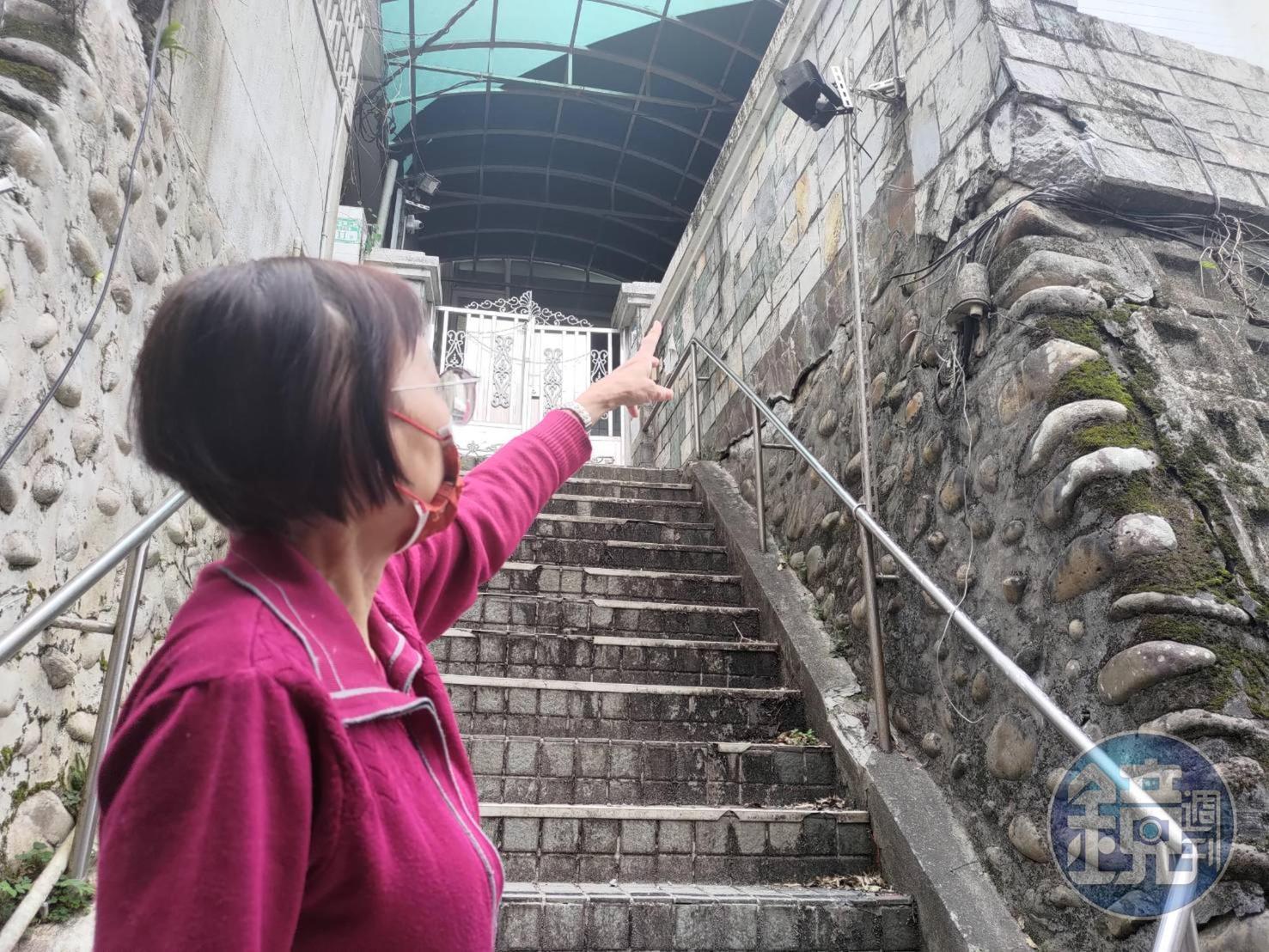 丁婦指著鄰居的建物，指控因其興建駁坎等違建，壓毀自家車庫。