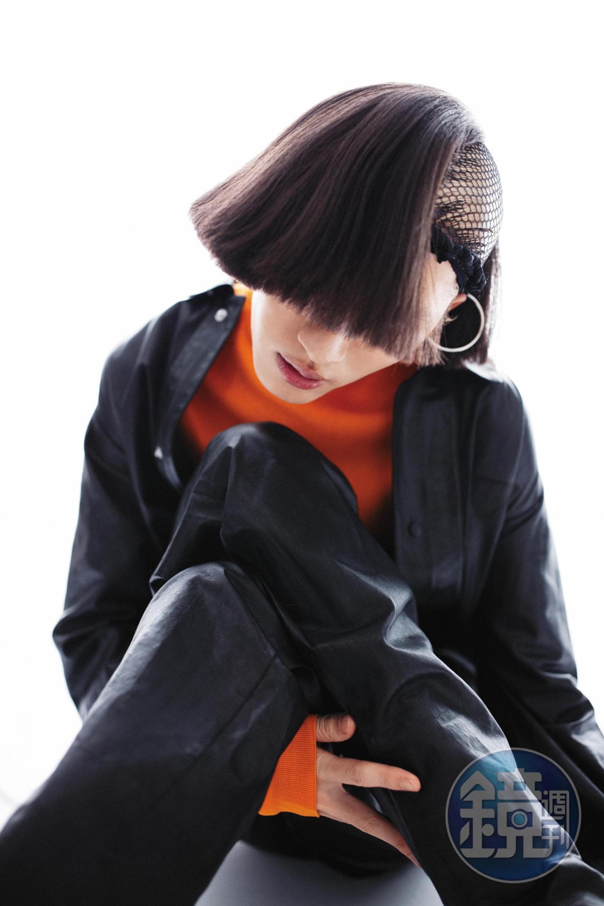 黑色連身皮褲，價格店洽 by PRADA；橘色高領上衣 價格店洽，by PRADA。