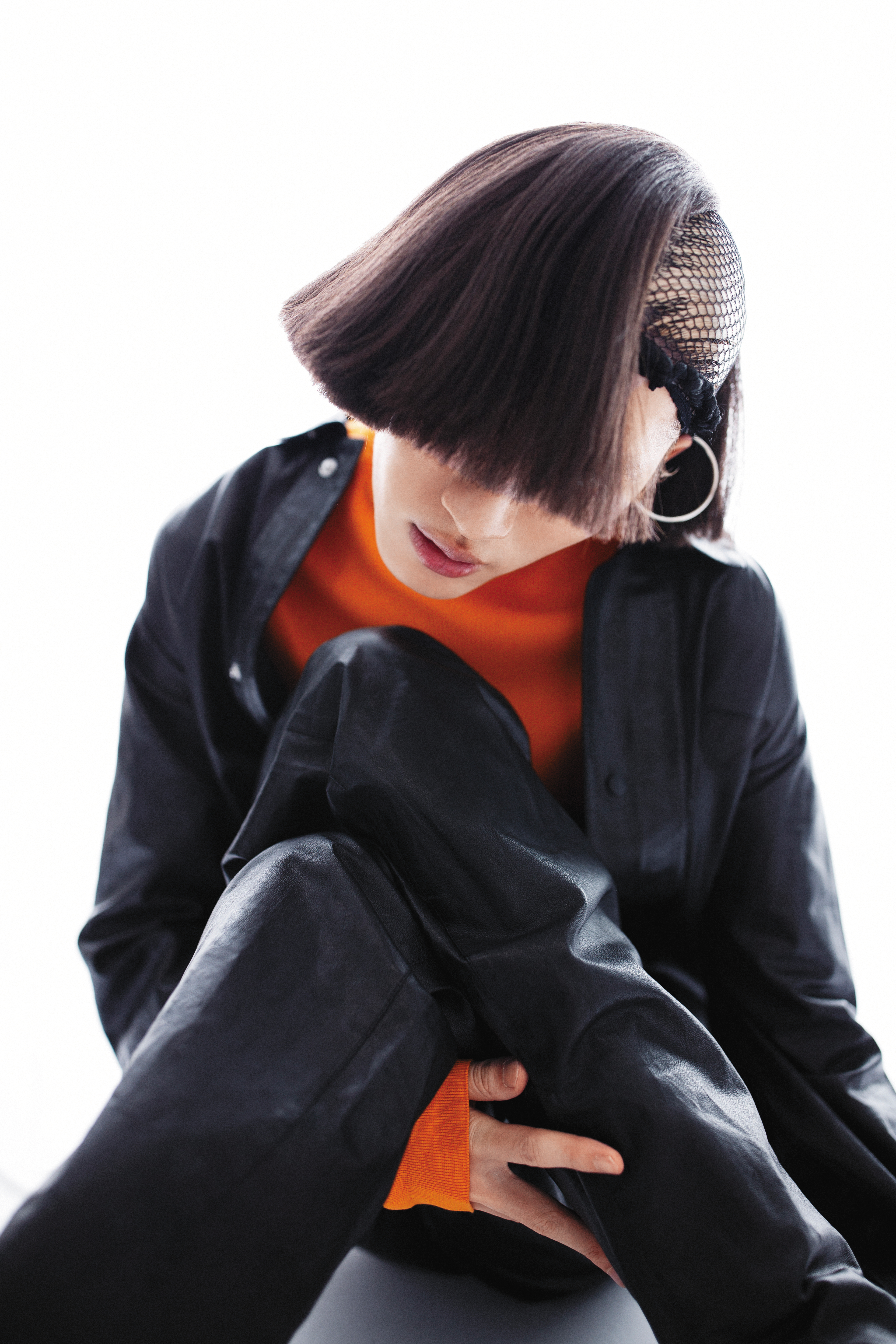 黑色連身皮褲，價格店洽 by PRADA；橘色高領上衣 價格店洽，by PRADA。
