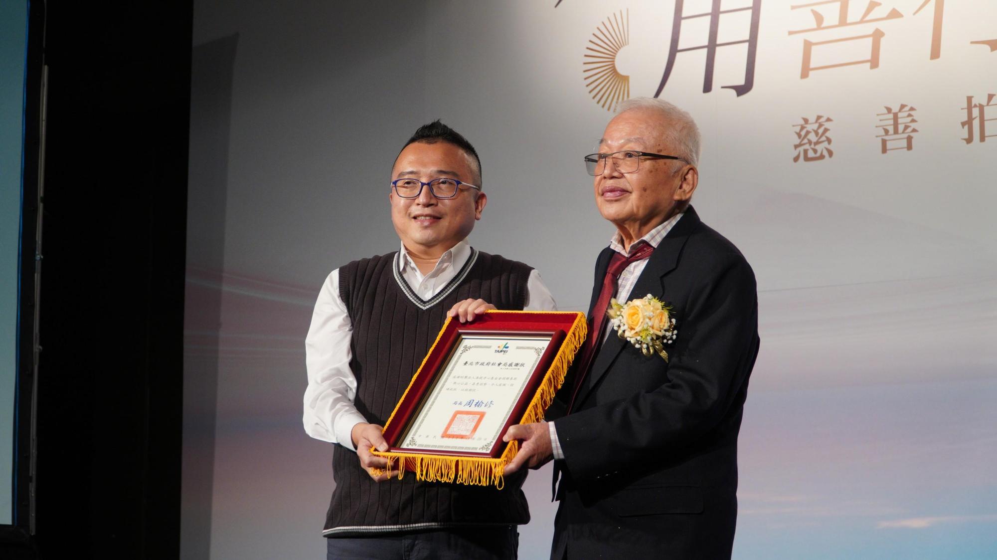 台北市政府社會局長周榆修頒贈感謝狀予基金會，由董事長劉泰英代表接受。（准提淨心基金會提供）