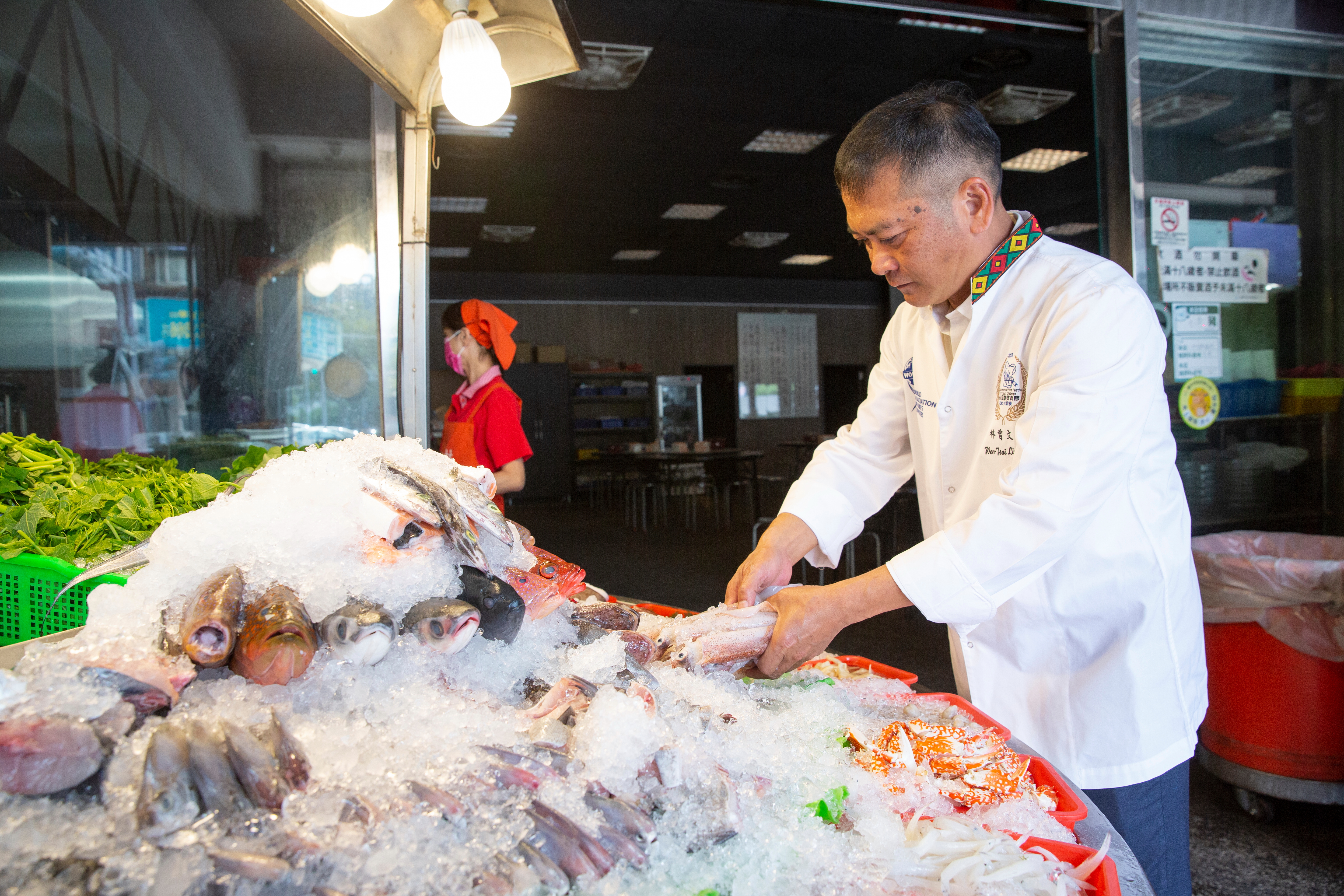 林曾文財（右）對海鮮食材的挑選功力，來自早年在日本料理店打下的基礎，他設計一目瞭然的立體擺放方式，方便饕客點選。