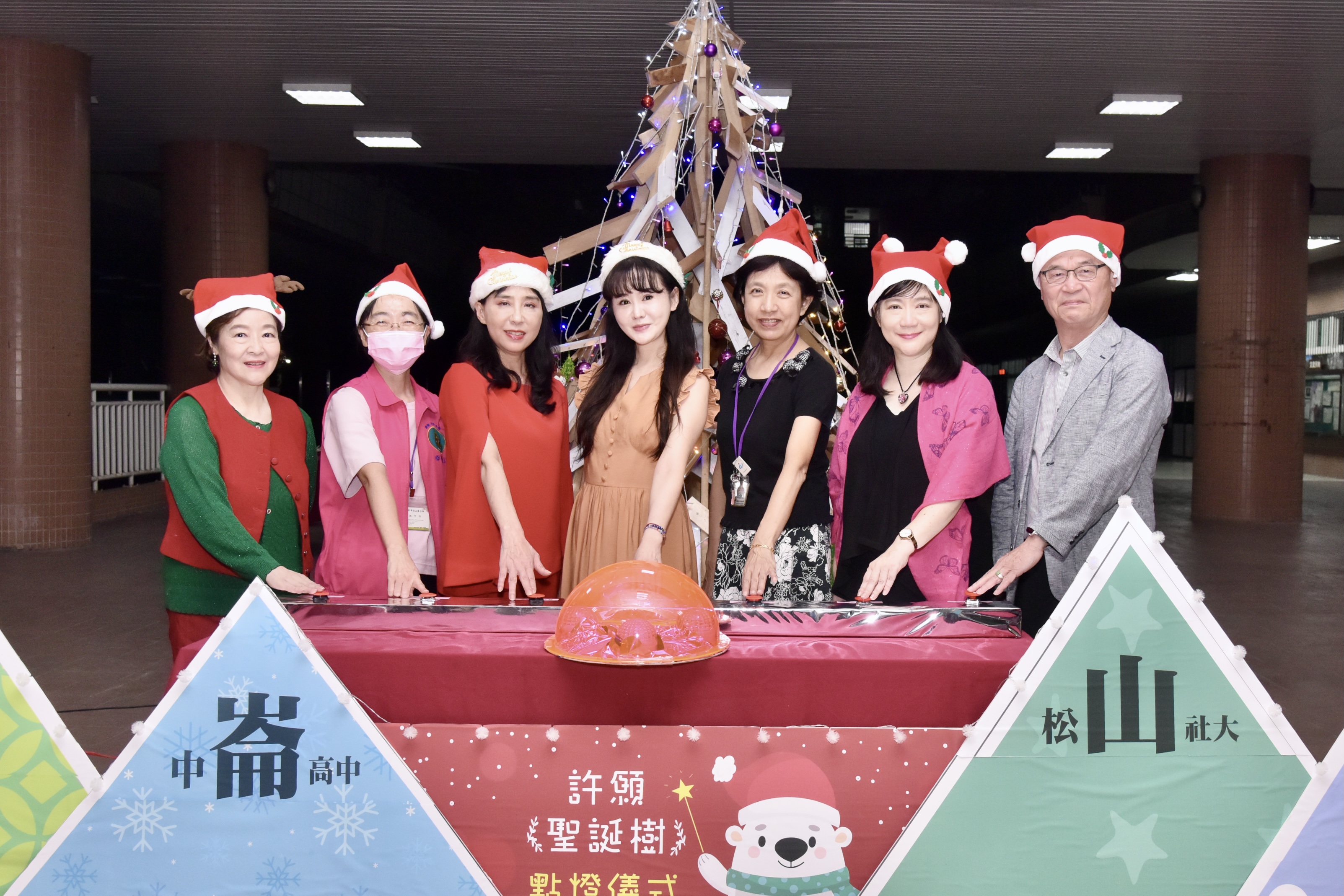 松山社大聖誕點燈由張如君主持，共同點燈人分別為詹媽媽、松山區長游竹萍、文道慈善基金會董事長蘇文玉、張如君、中崙高中校長劉晶晶、松山社大校長劉熒瑰、Hi-Q總經理陳樹人。（松山社區大學提供）