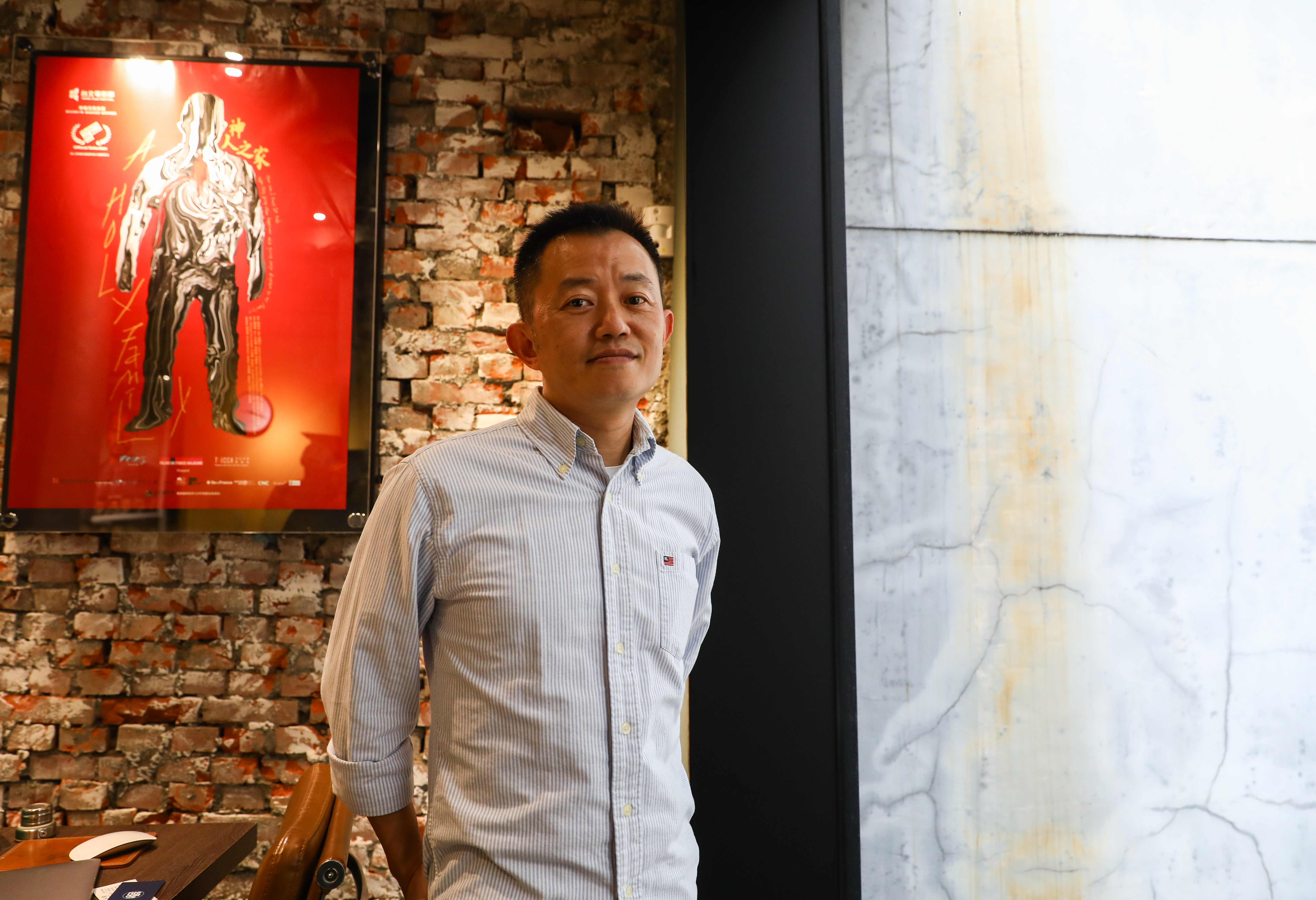 盧盈良在電影發行公司受訪，背後是《神人之家》的海報。他說電影能拍成是緣分，得獎、上映都是緣分，而最重要的緣分，在於和家人的重新凝聚。