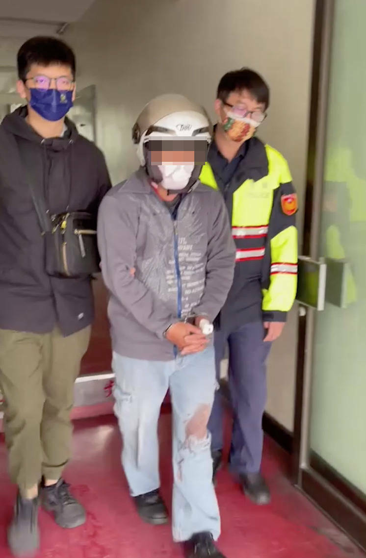 林男行凶後被扭送警局，警方移送時，他褲子還有血跡。（讀者提供）