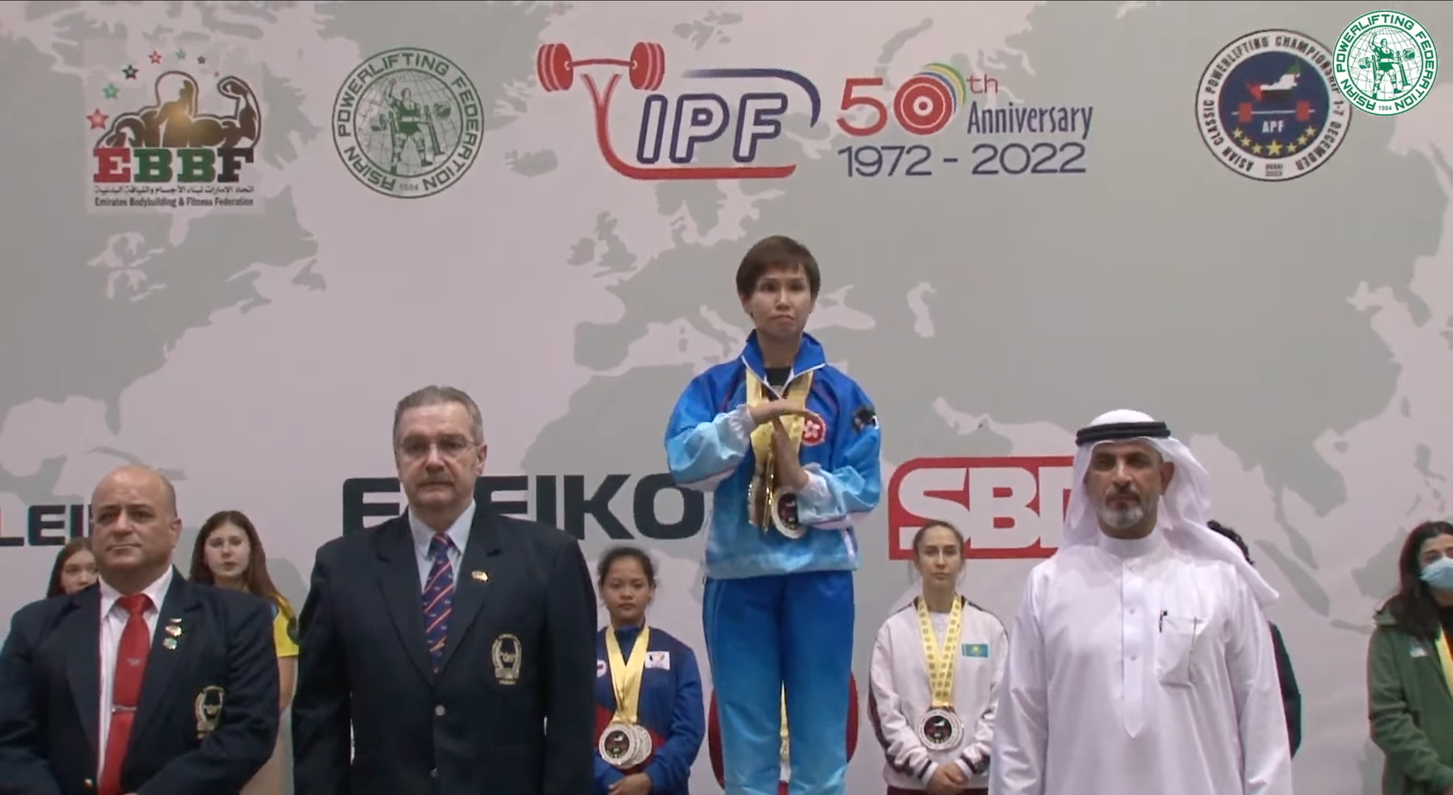 杜拜舉辦的「2022亞洲經典健力錦標賽」，在香港選手連煒楨（中）的頒獎儀式上播放〈願榮光歸香港〉，讓她急比「T」喊停。（翻攝自YouTube）