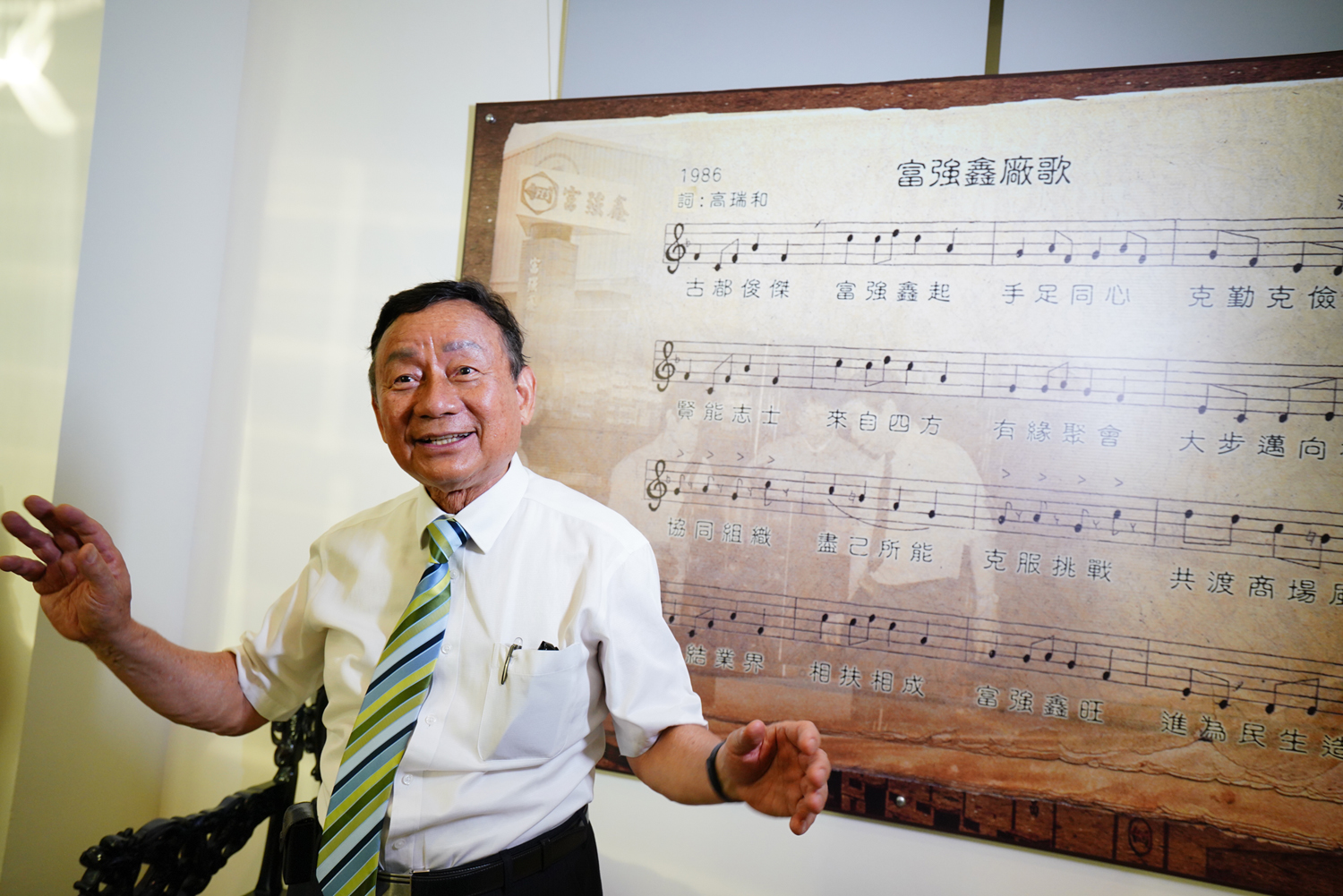 富強鑫大廳的牆面貼著廠歌歌譜，歌詞道盡富強鑫創業史，也藏著王伯壎二個兒子的名字「傑」、「賢」二字。