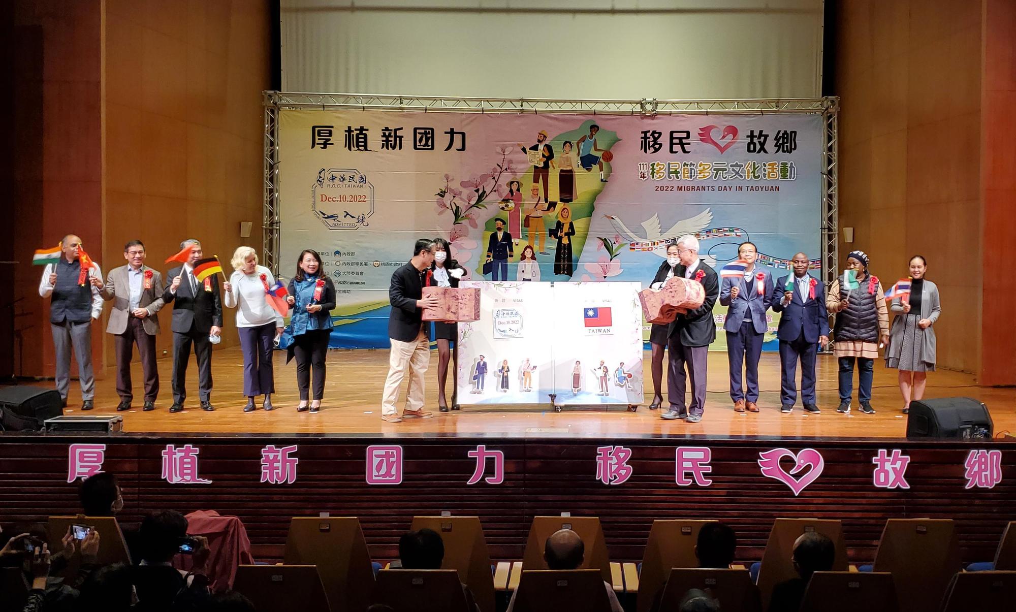 移民署署長鐘景琨(左6)與桃園市副市長李憲明(右5),分別於魔法書上蓋下象徵中華民國入境查驗章及國旗,揭開移民節活動序幕。(移民署提供)