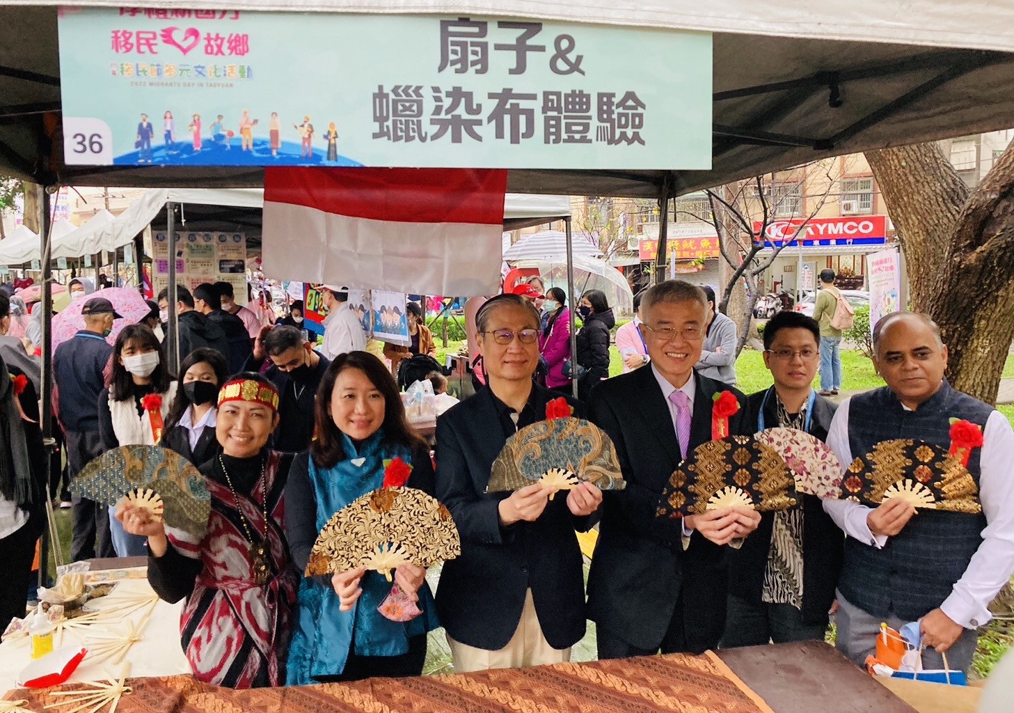 移民署署長鐘景琨（右4）、桃園市副市長李憲明（右3）及印尼代表處郭進來專員一同逛桃園新市集攤位,體驗手作印尼蠟染扇子。（移民署提供）