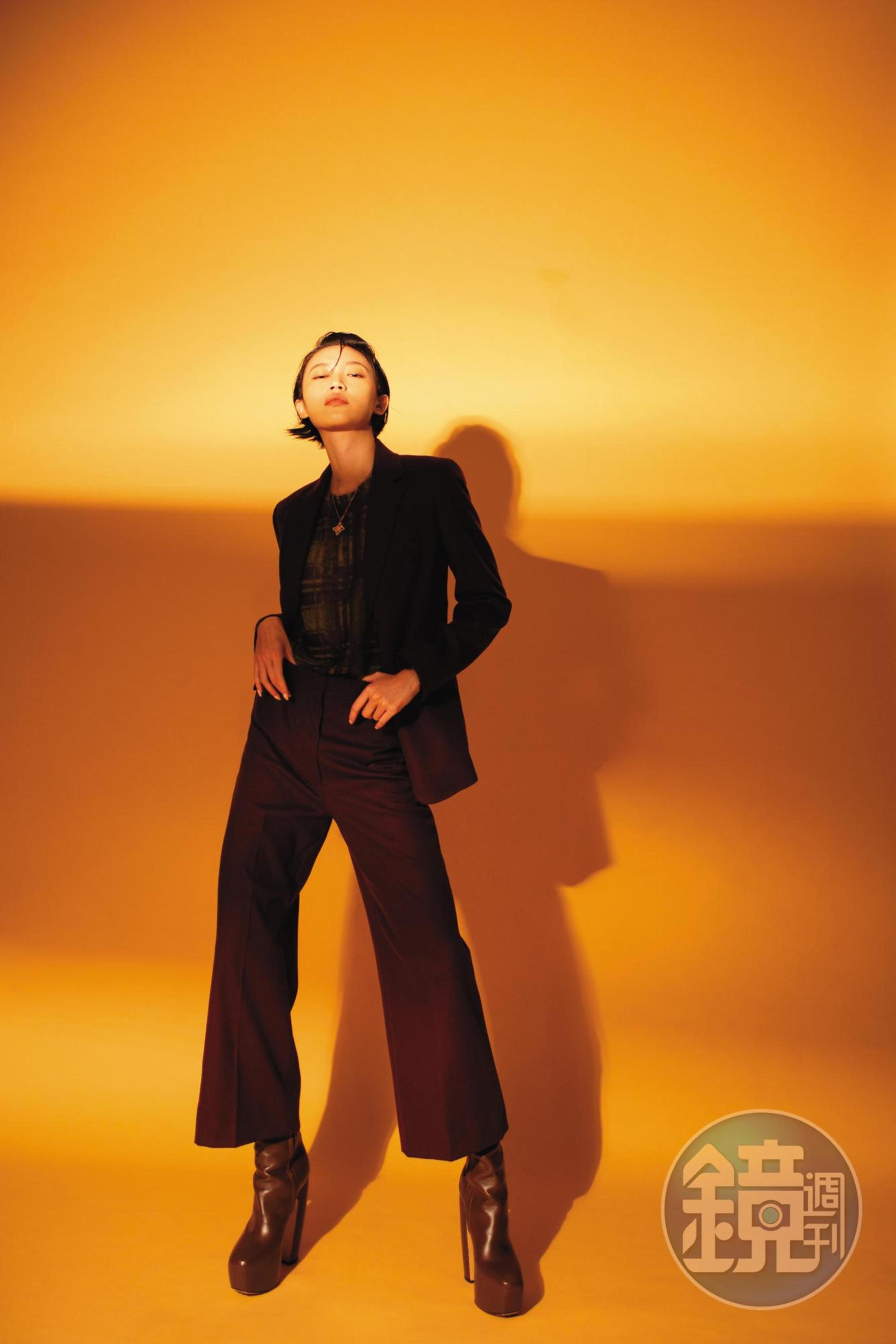 紫紅色修身長褲 NT$20,800 by Max Mara；紫紅色西裝外套 NT$45,800 by Max Mara；透膚格紋內搭 NT$26,800 by Max Mara；深棕色高跟長靴 價格店洽 by BOTTEGA VENETA；Wulu Legend系列18K玫瑰金鑲鑽紅寶石項鍊 NT$185,500 by Qeelin。