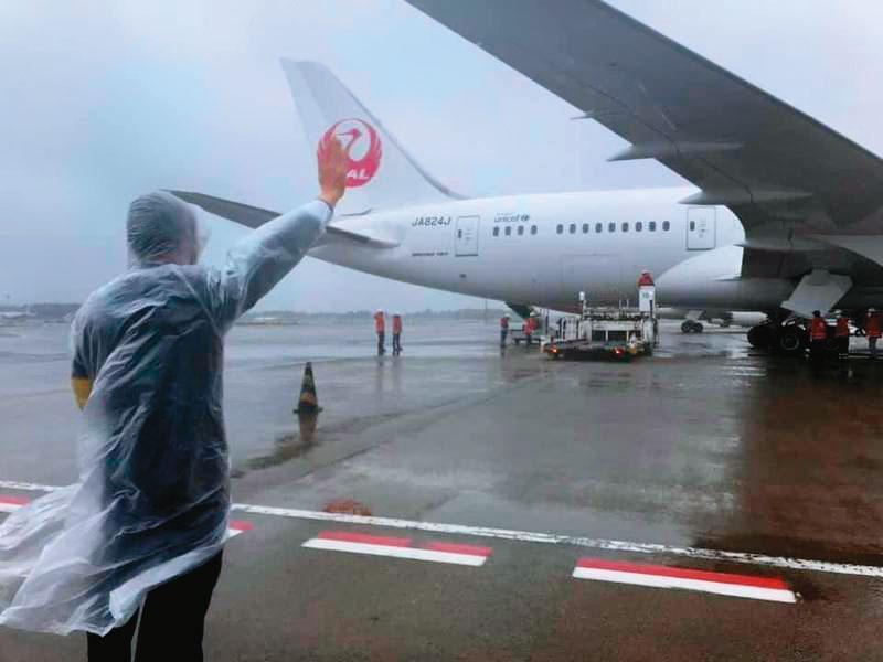 去年6月，日本政府捐贈台灣約124萬劑AZ疫苗，謝長廷冒雨到機場確認疫苗上機，並向機組人員致意。（翻攝謝長廷臉書）