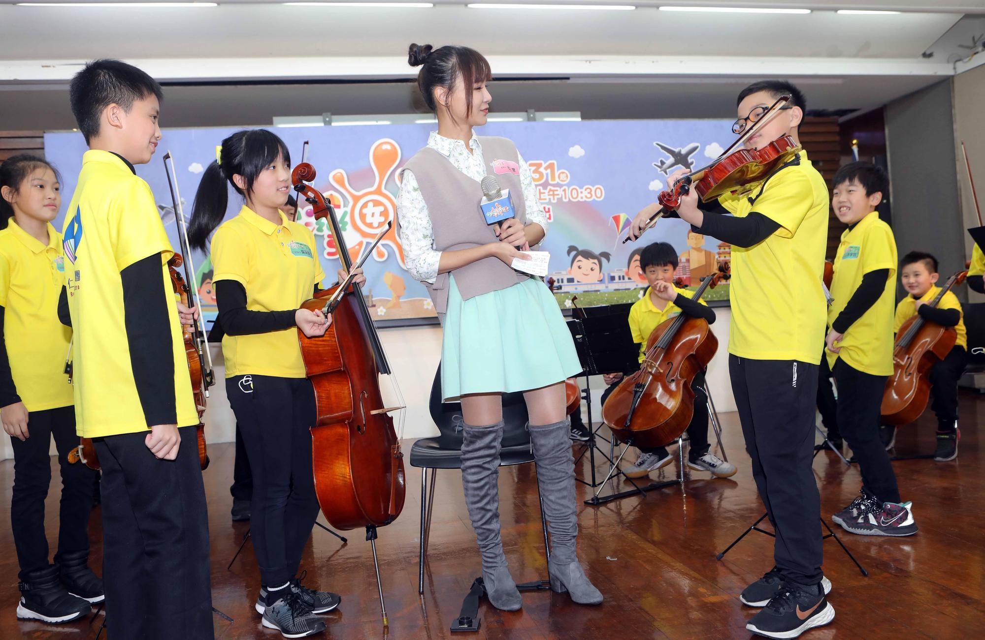 主持人亞里（中）在《台灣囡仔，讚！》第14季記者會上欣賞基隆市仁愛國小帶來優美的絃樂演奏。（公視提供）