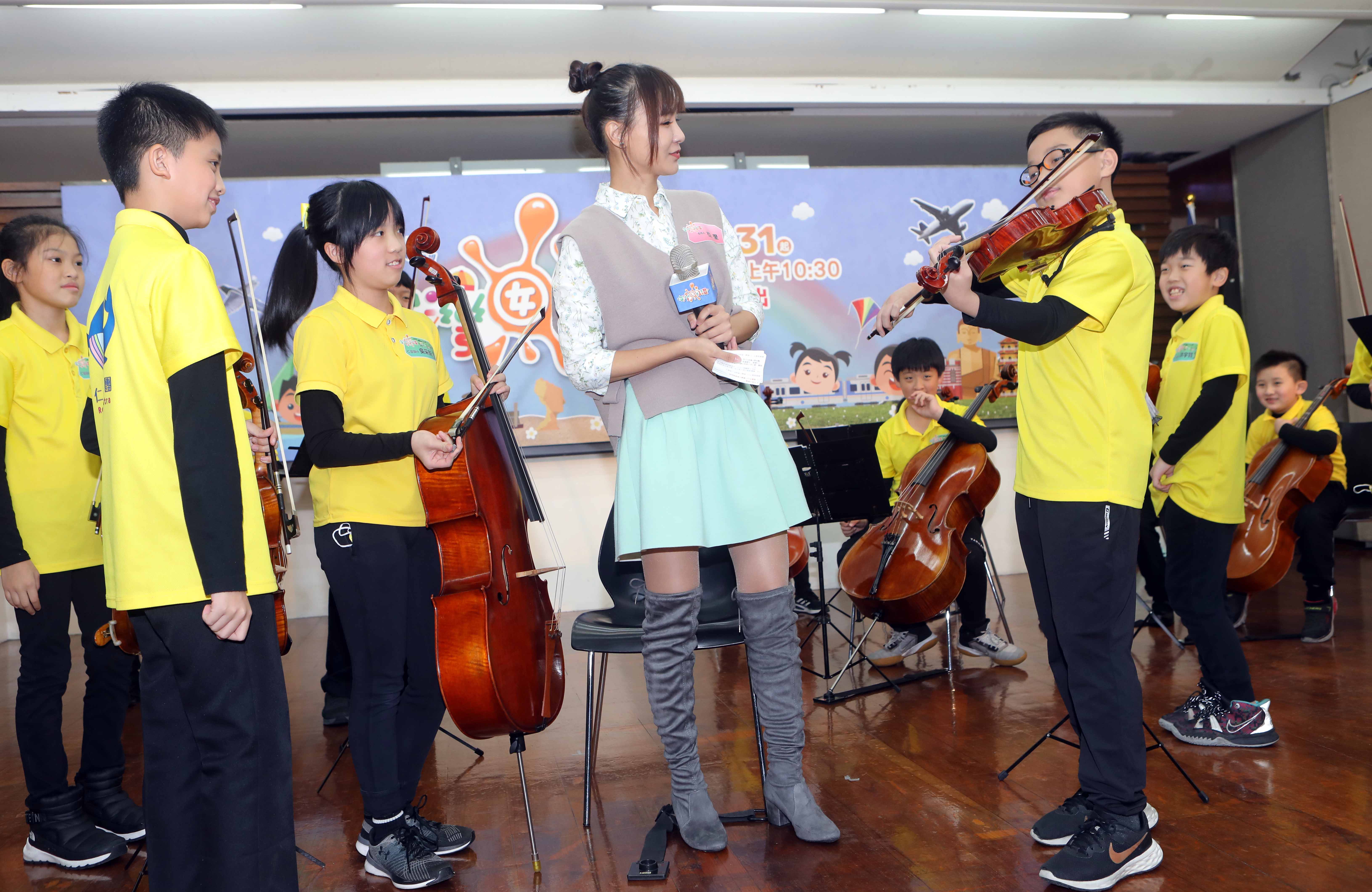 主持人亞里（中）在《台灣囡仔，讚！》第14季記者會上欣賞基隆市仁愛國小帶來優美的絃樂演奏。（公視提供）