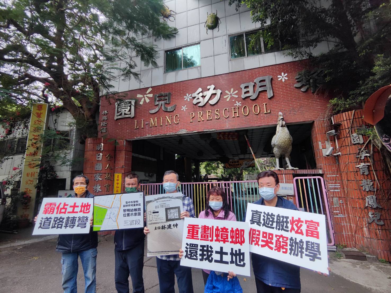 多名地主聚集在台中黎明幼兒園前，手持標語控訴園長林金連以土地正義為藉口霸地不還。（讀者提供）