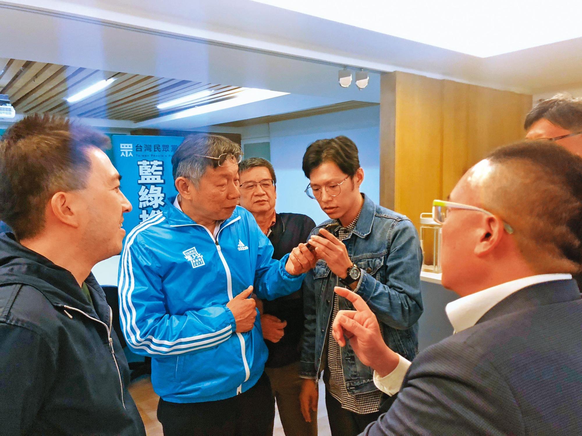 謝泊泓（拿手機者右）是柯文哲（拿手機者左）核心幕僚，2020年大選開票之夜本刊專訪柯時，他更是少數陪同受訪的幕僚。（黃驛淵攝）