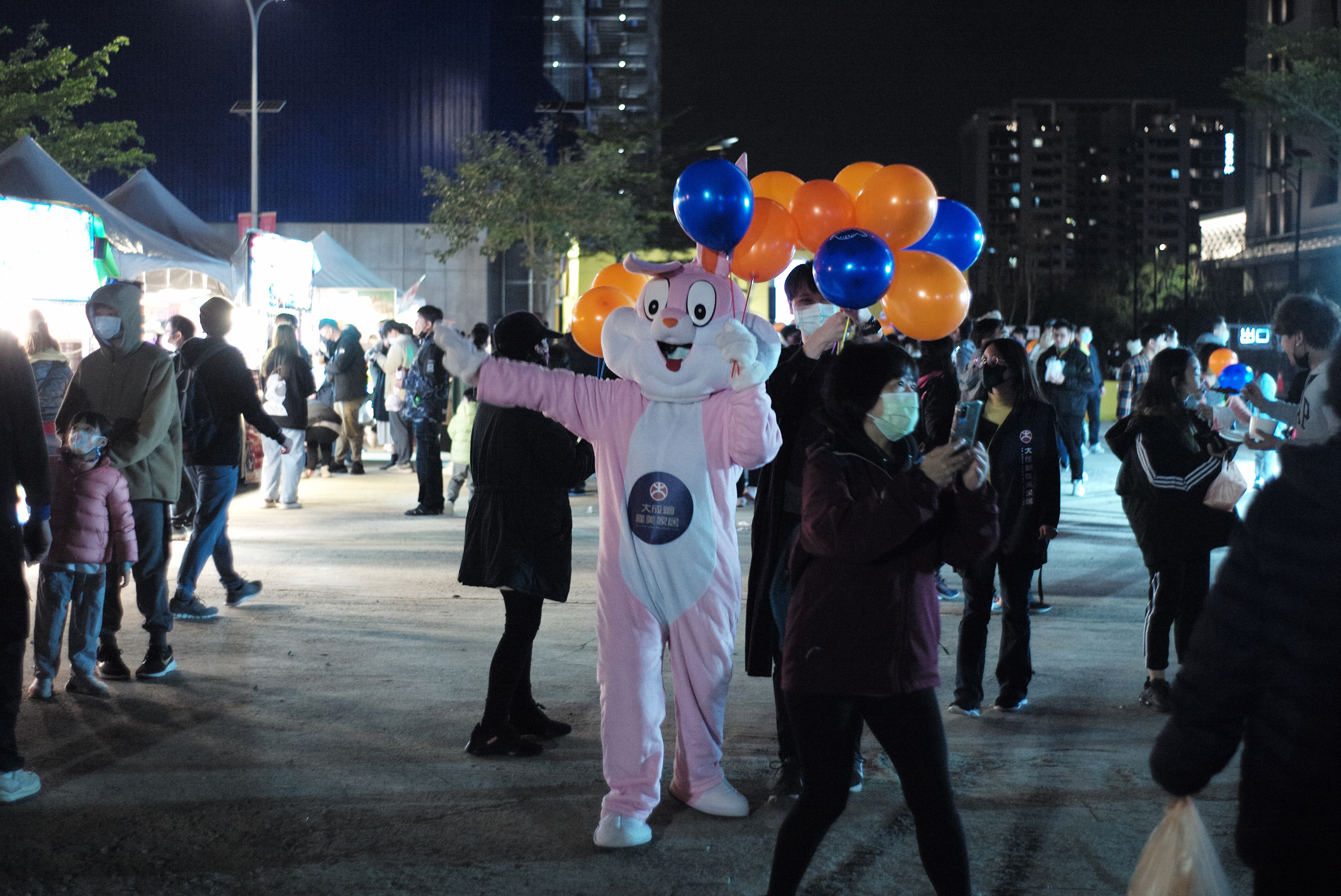 在夜晚人群中發氣球的兔兔。