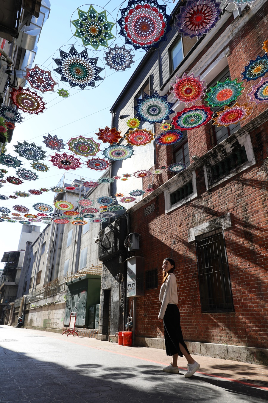 藝術家楊海茜鉤織作品《繁花紅》，從餐館柳梢青端延伸至對面的太陽餅博物館。