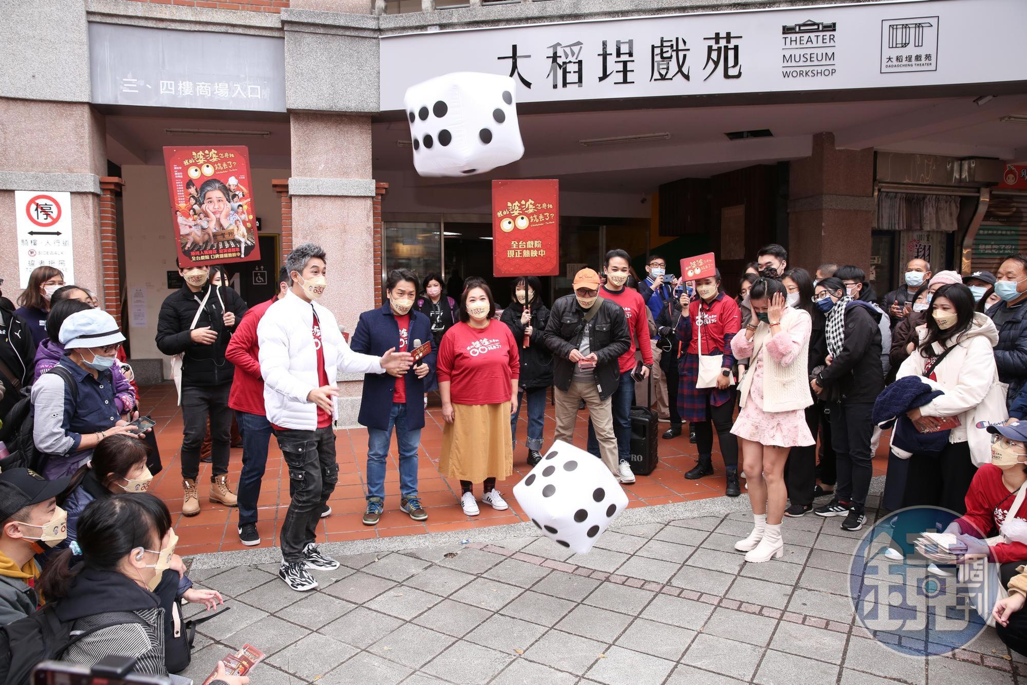 眾人在廣場與遊客玩擲骰子遊戲,一群人玩得十分開心。